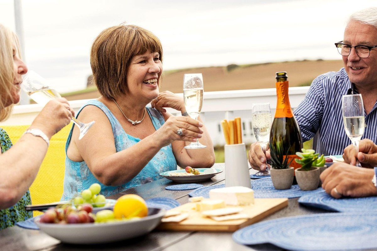 Group of people round table enjoying meal and glass of bubbly wine