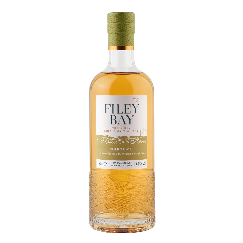A bottle of Filey Bay Nurture single malt whisky with a golden hue, featuring a textured base and a green cork.
