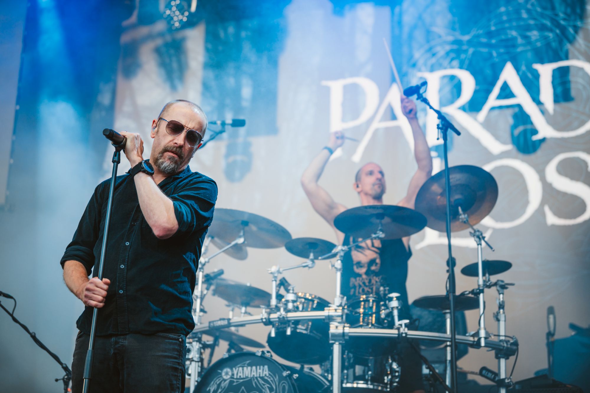 Rock band performing on stage with vibrant lighting and smoke