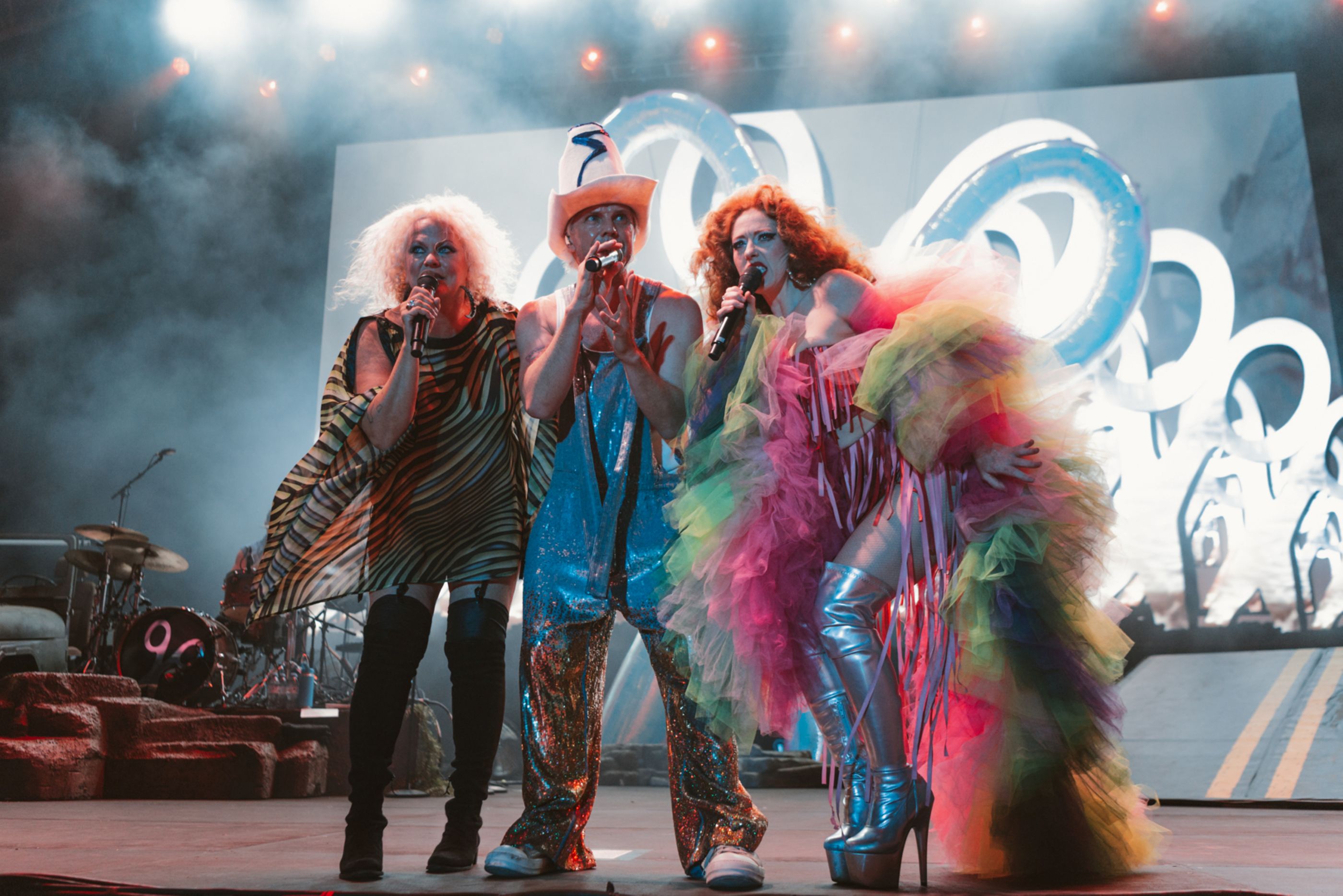 Colourful performers on stage with dramatic lighting