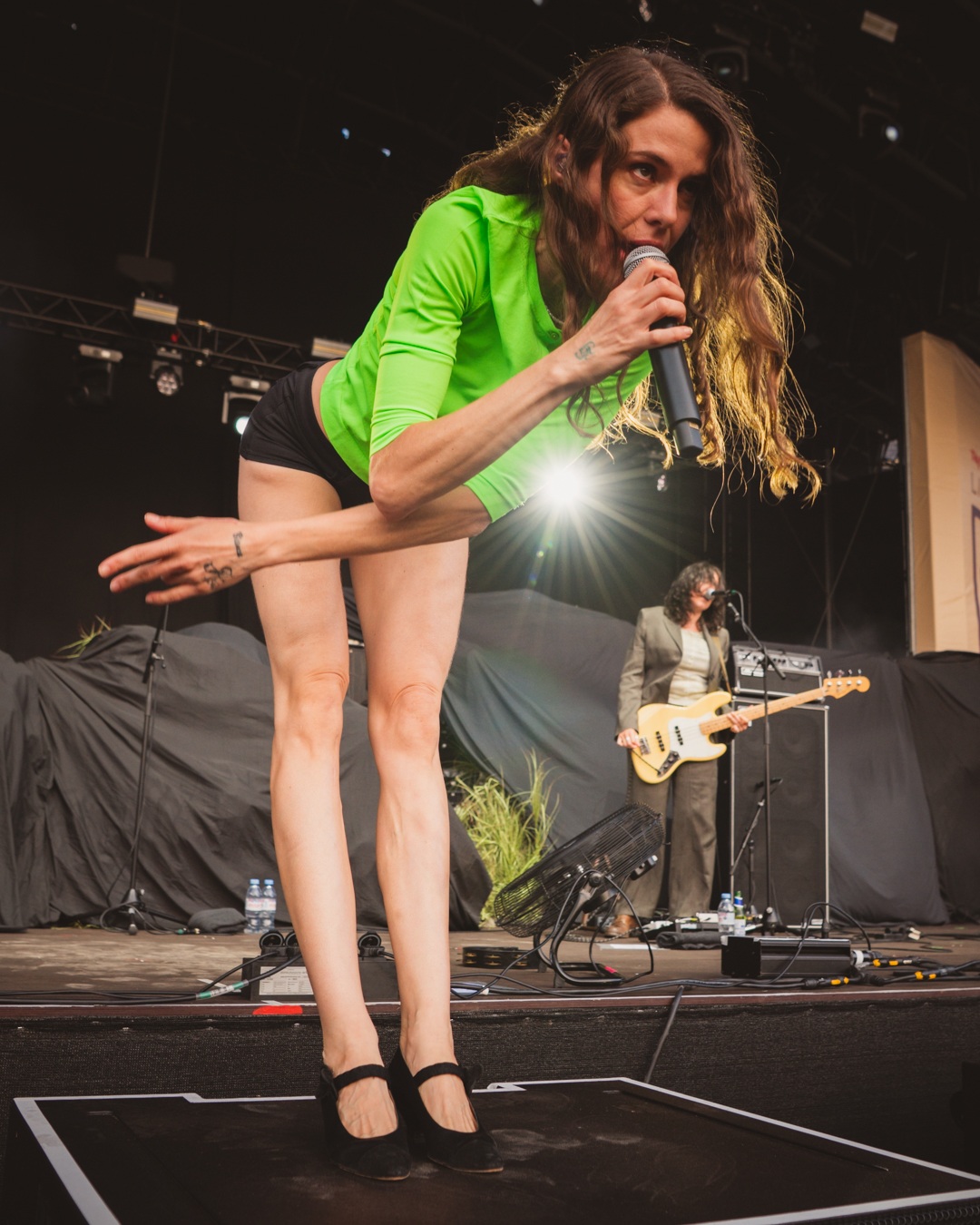 Performer in green top singing on stage with guitarist