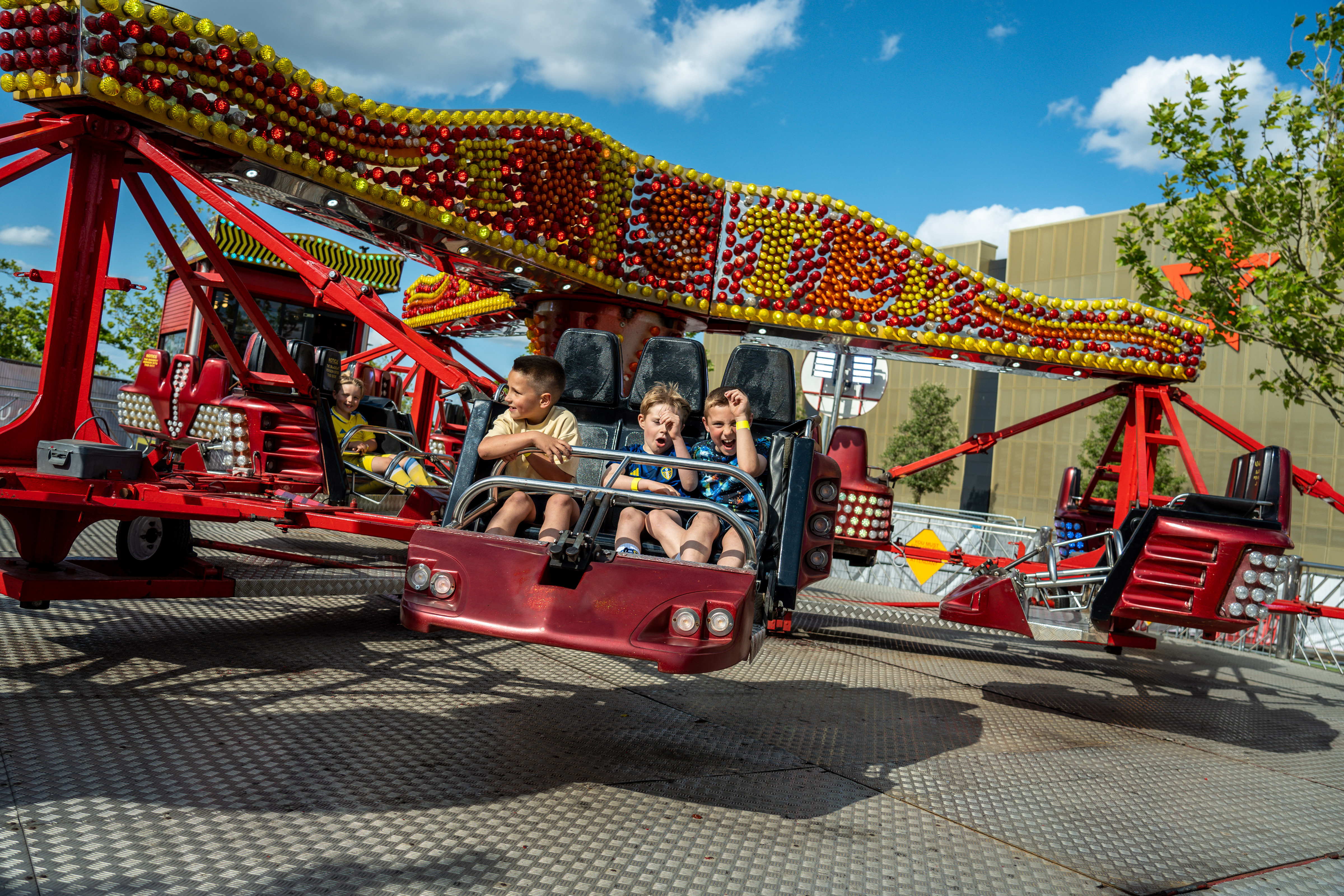 Children enjoying a colorful spinning ride under blue sky