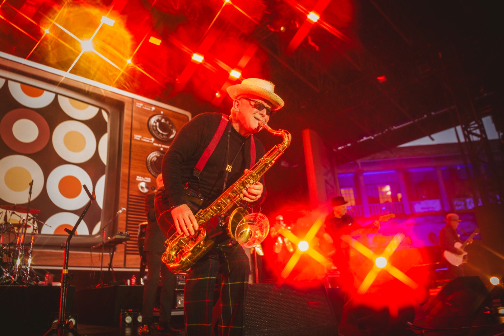 Jazz musician playing saxophone onstage with vibrant red lights