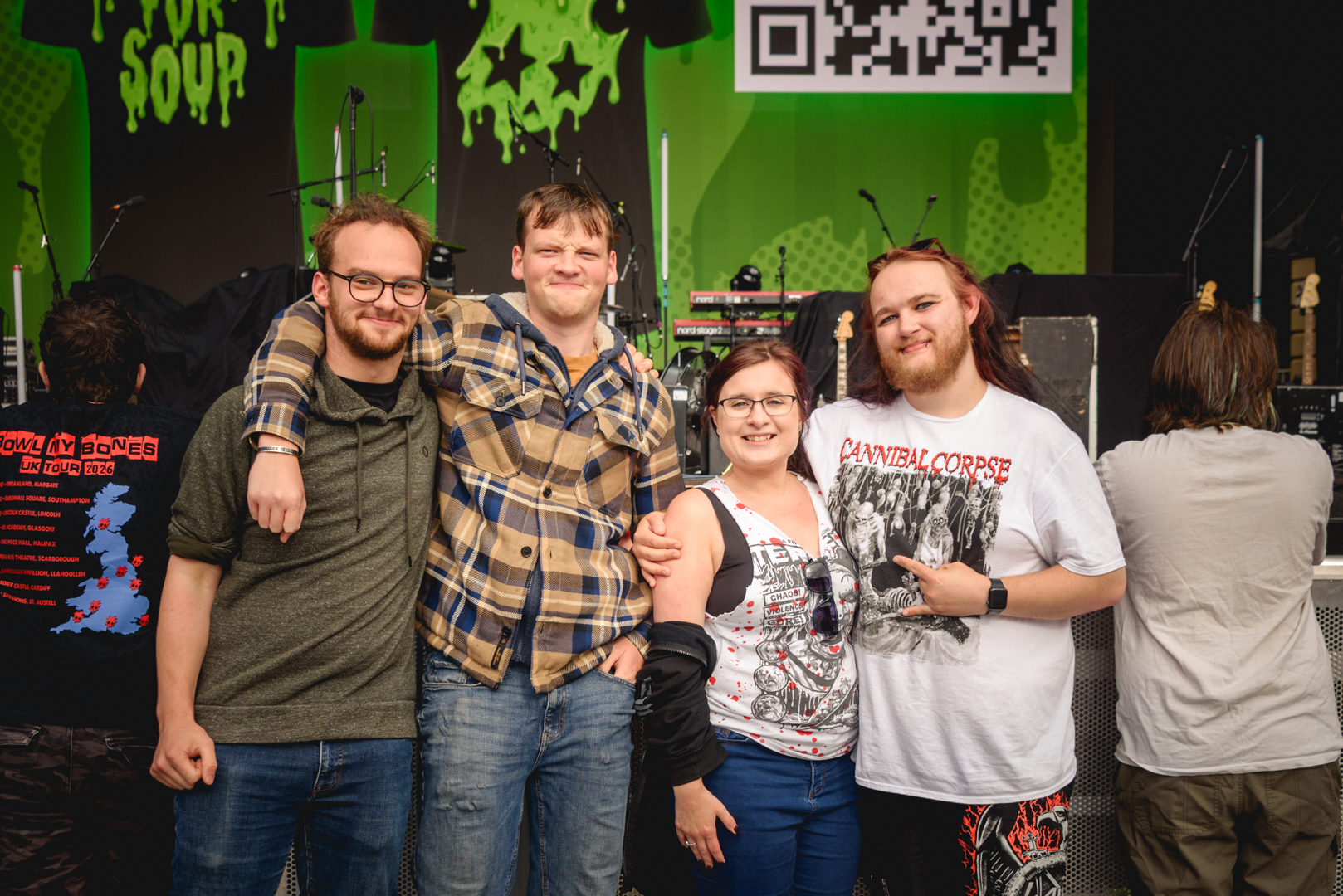 Group of four friends smiling in front of a concert stage