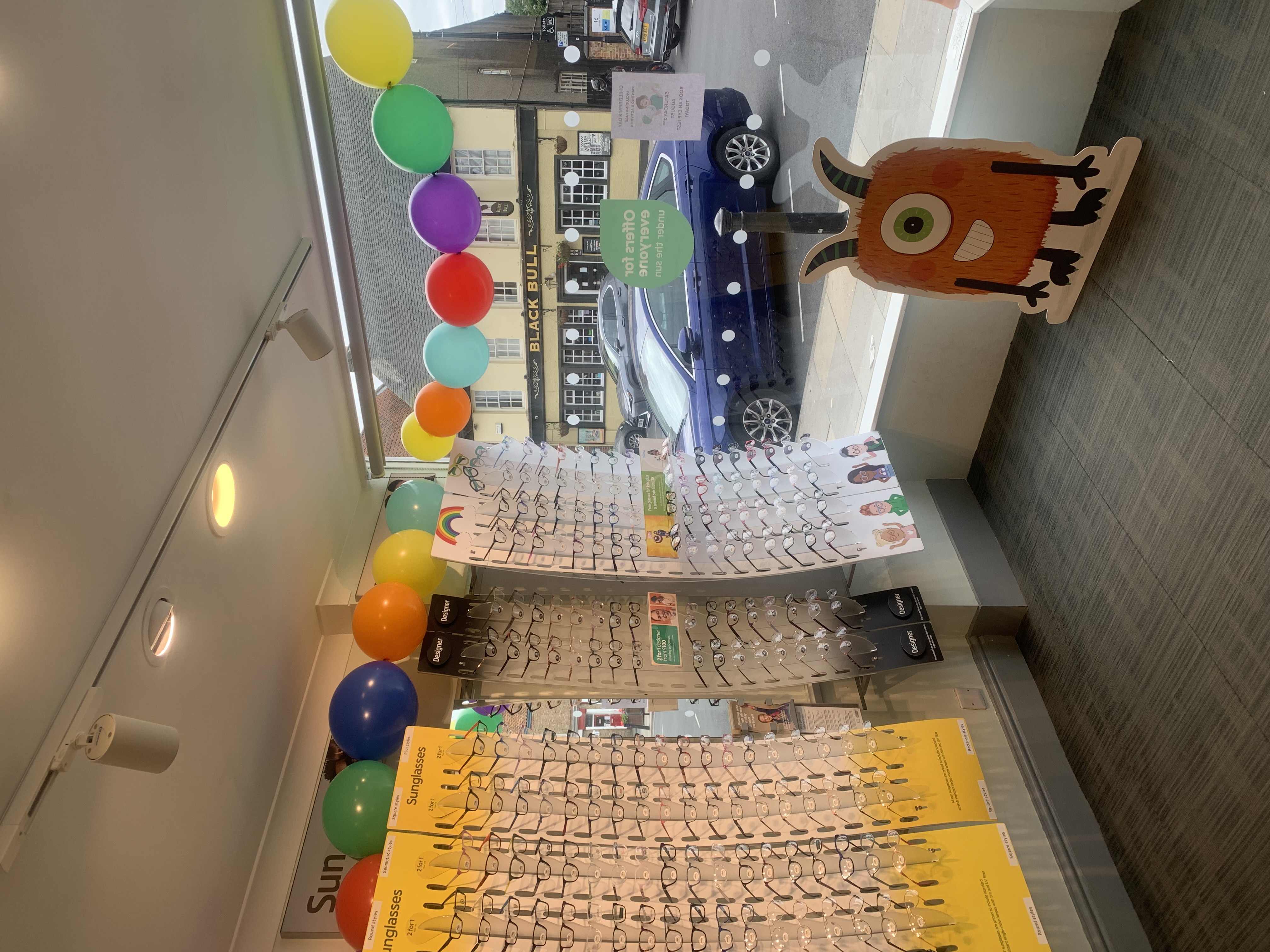 Optician display with colourful balloons and village street view