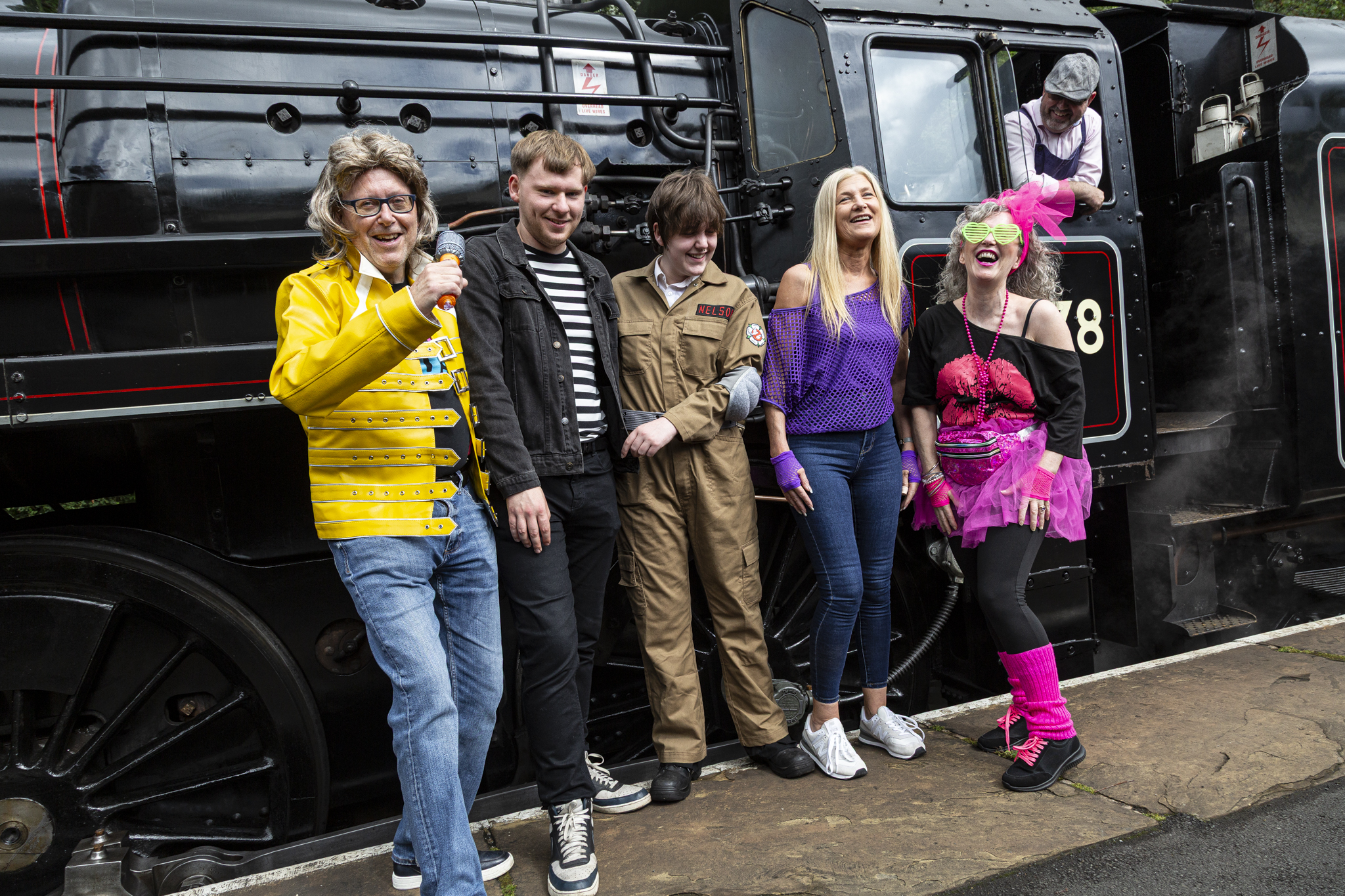Group in costumes laughing beside vintage steam train