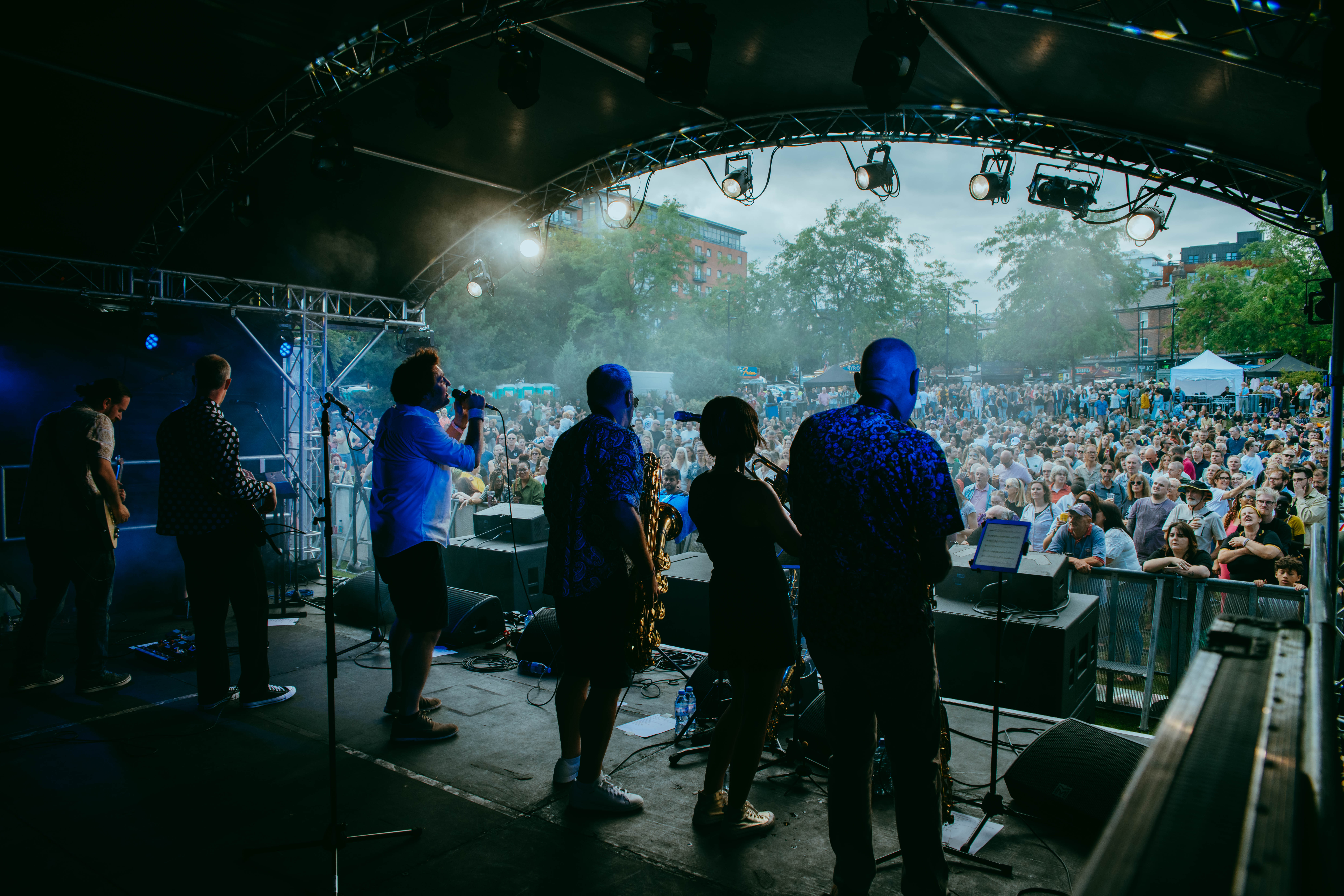 Band performing on stage at outdoor festival with crowd