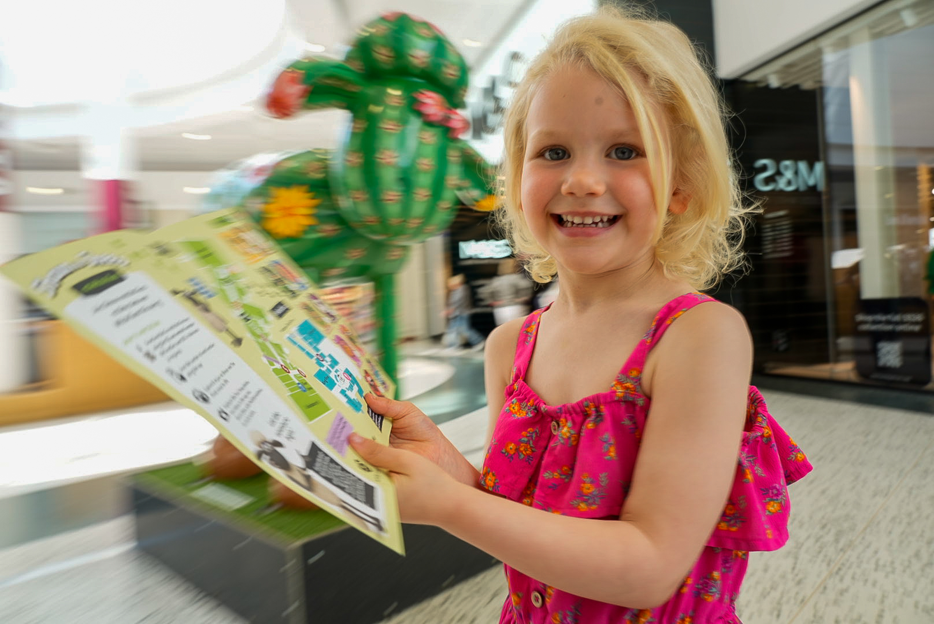 Smiling child holding a brochure in a shopping center