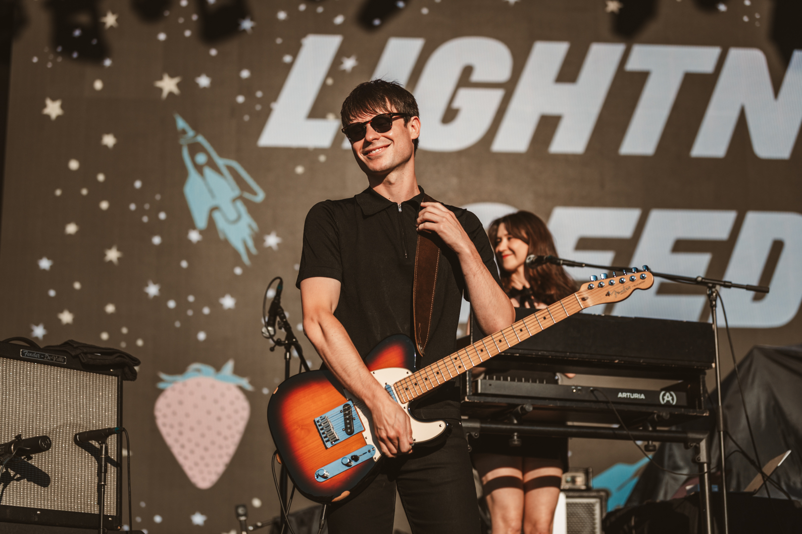 Musicians performing on stage with space-themed backdrop