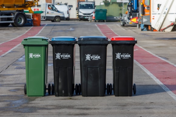 Four York-branded wheelie bins lined on concrete surface