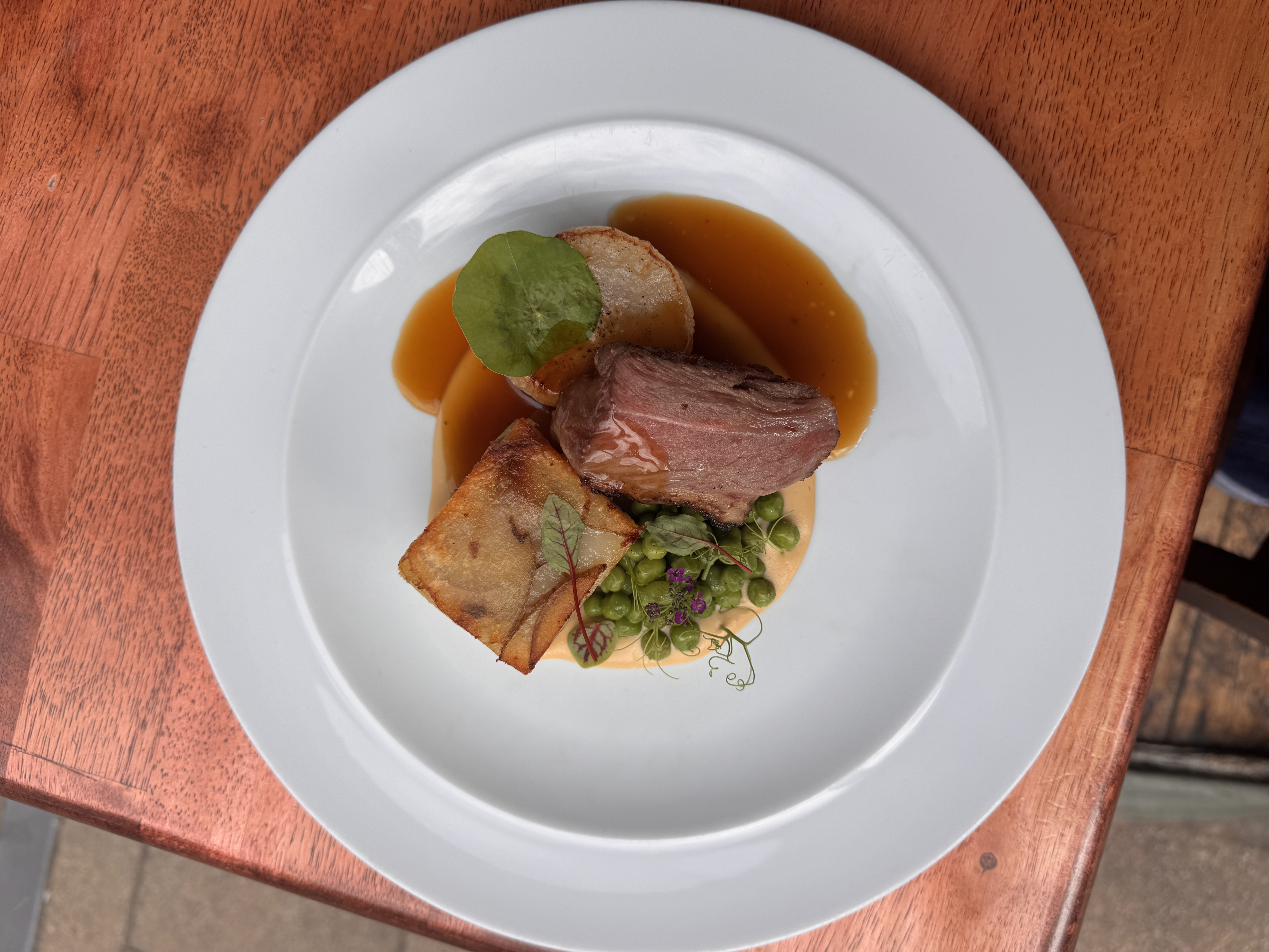 Gourmet dish with roast beef, potato, peas, and sauce