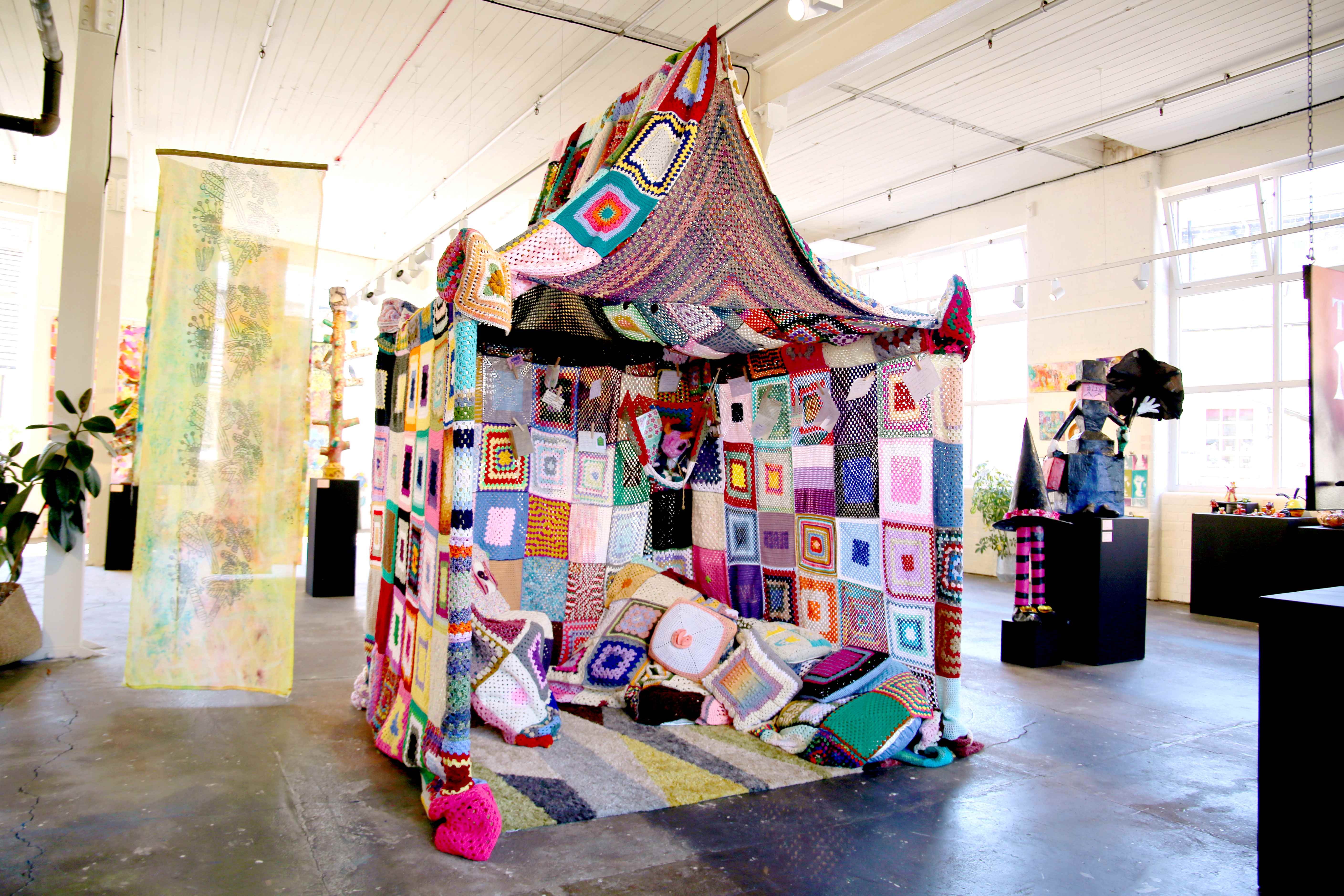 Colorful crochet tent with patchwork design in art gallery