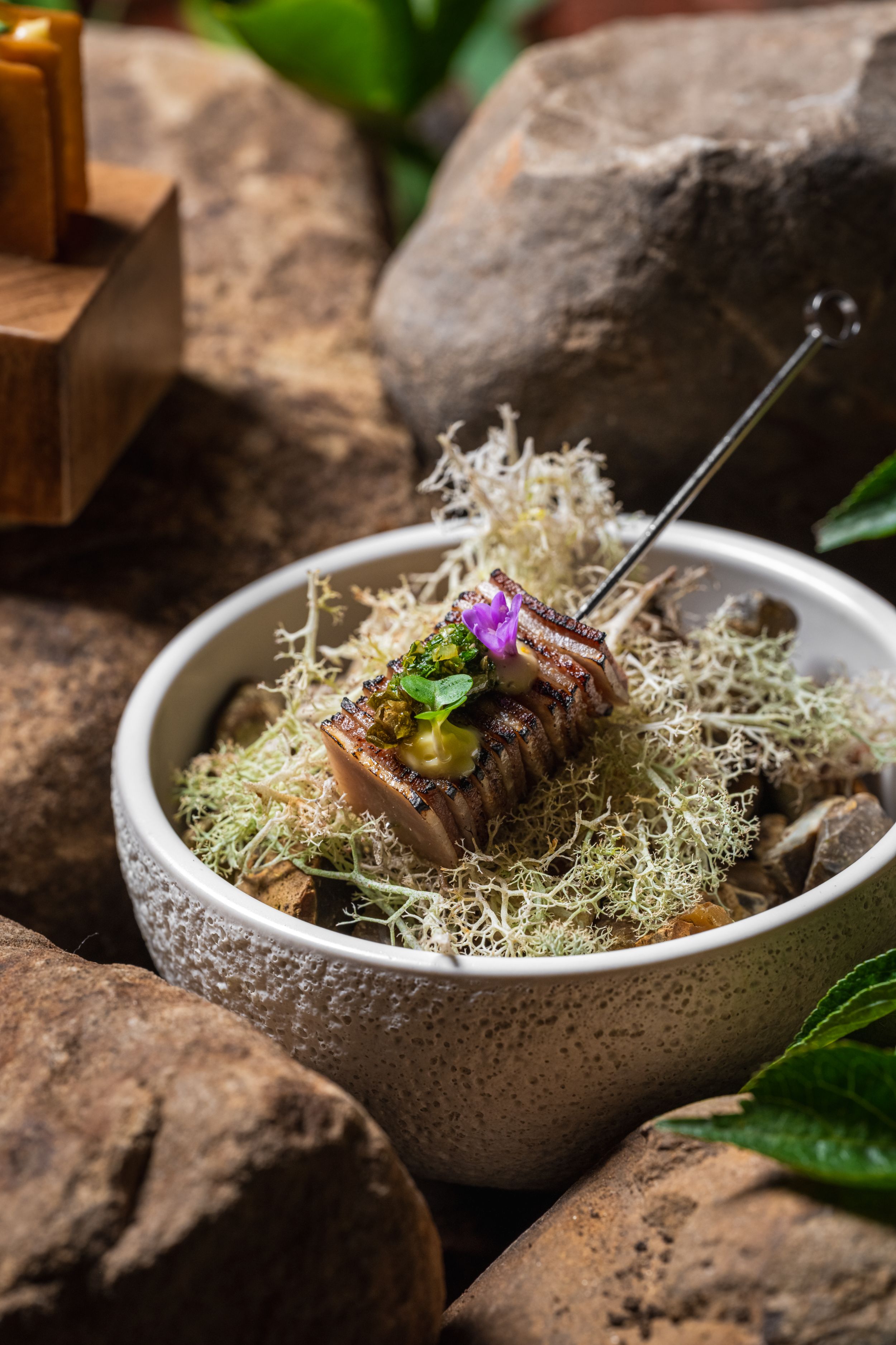 Gourmet dish of grilled fish on moss in rustic ceramic bowl