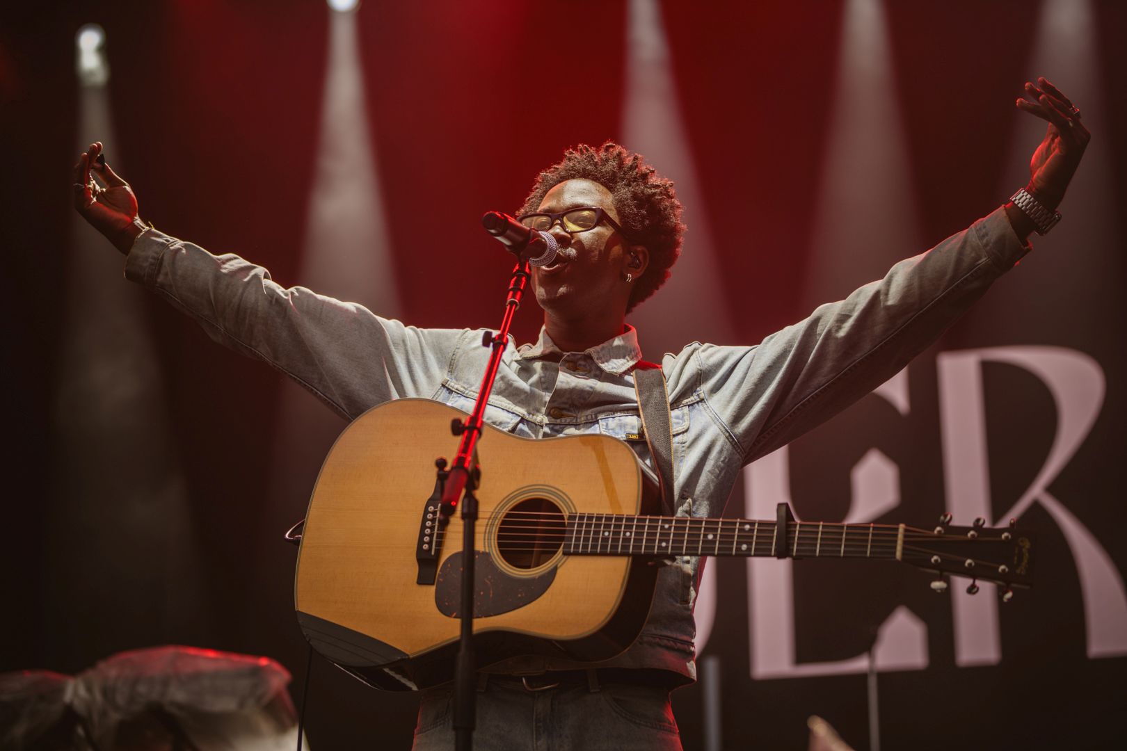 Musician on stage with guitar under red stage lights