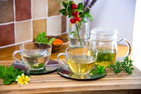 Two glass teacups with herbal tea on a wooden tray