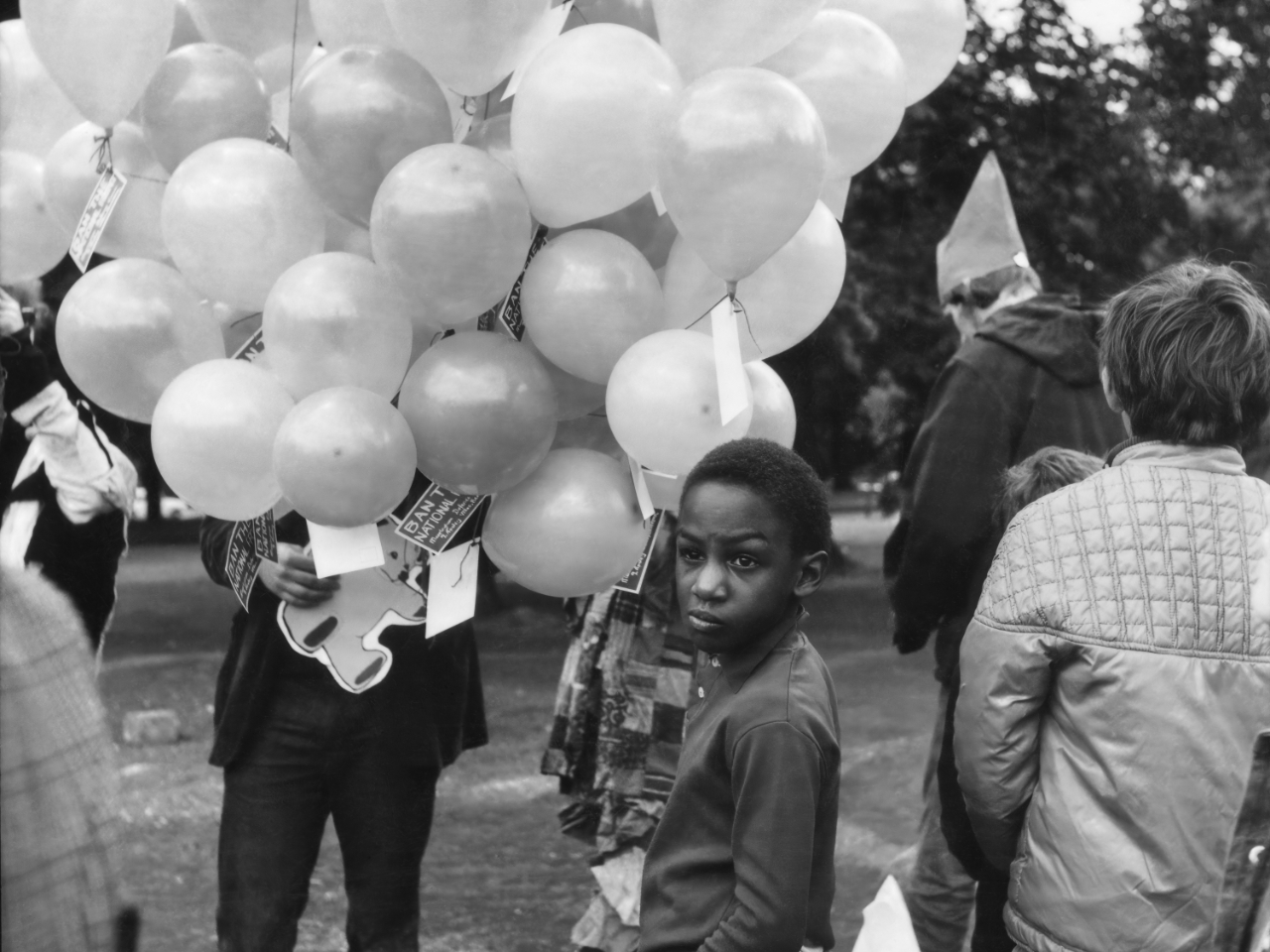 Child holding balloons at a lively outdoor festival