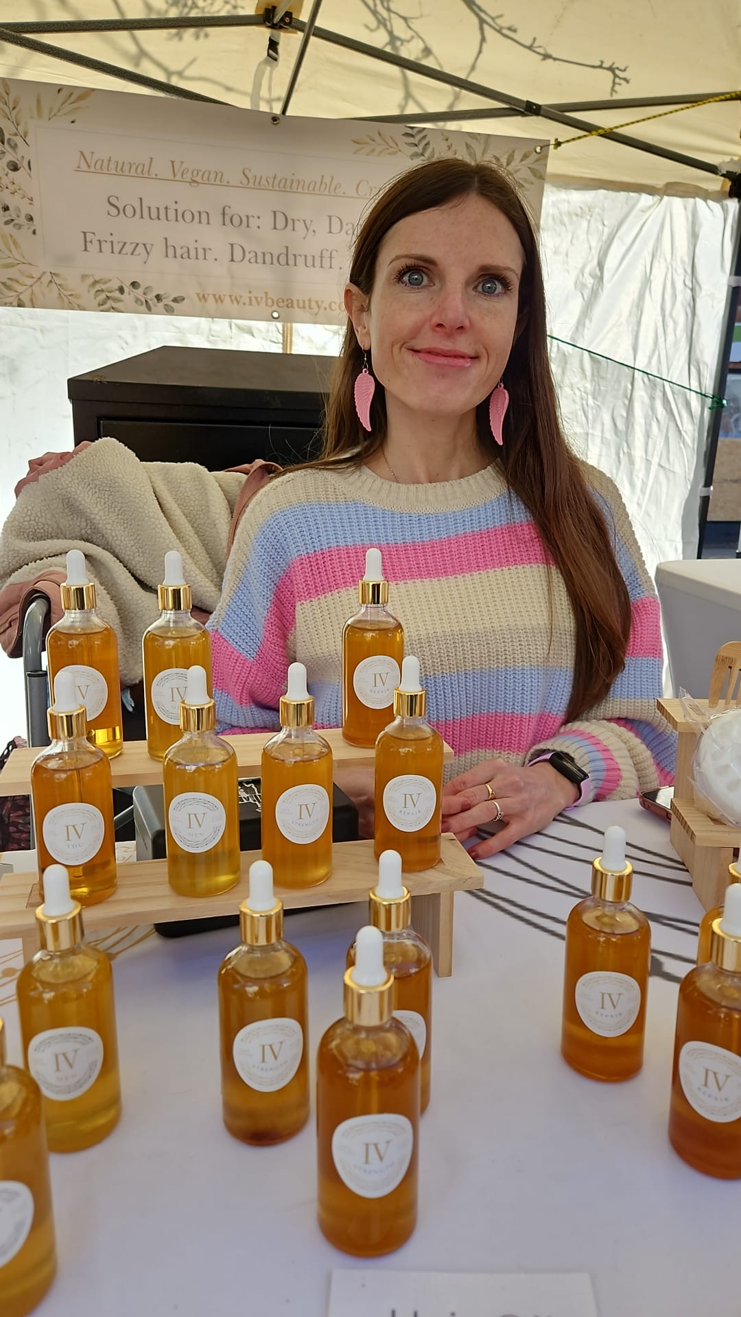 Smiling vendor with natural skincare oils at a market stall