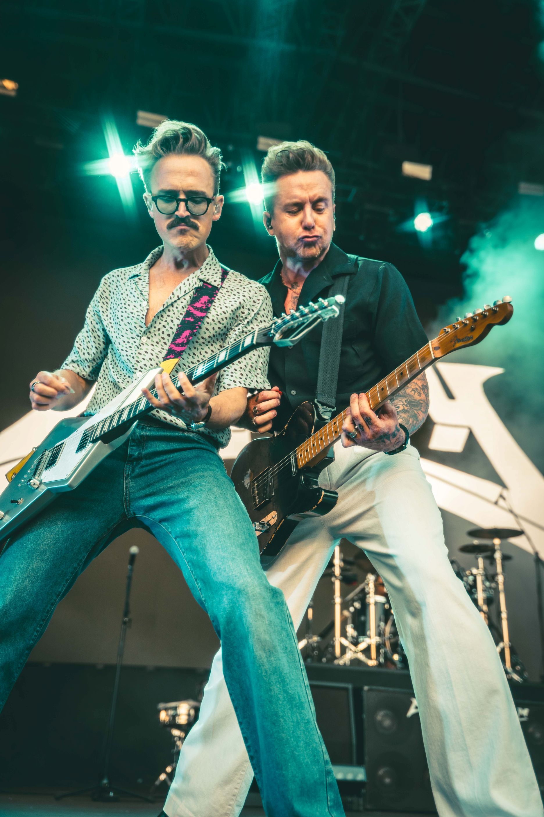 Two musicians playing electric guitars on stage with lights