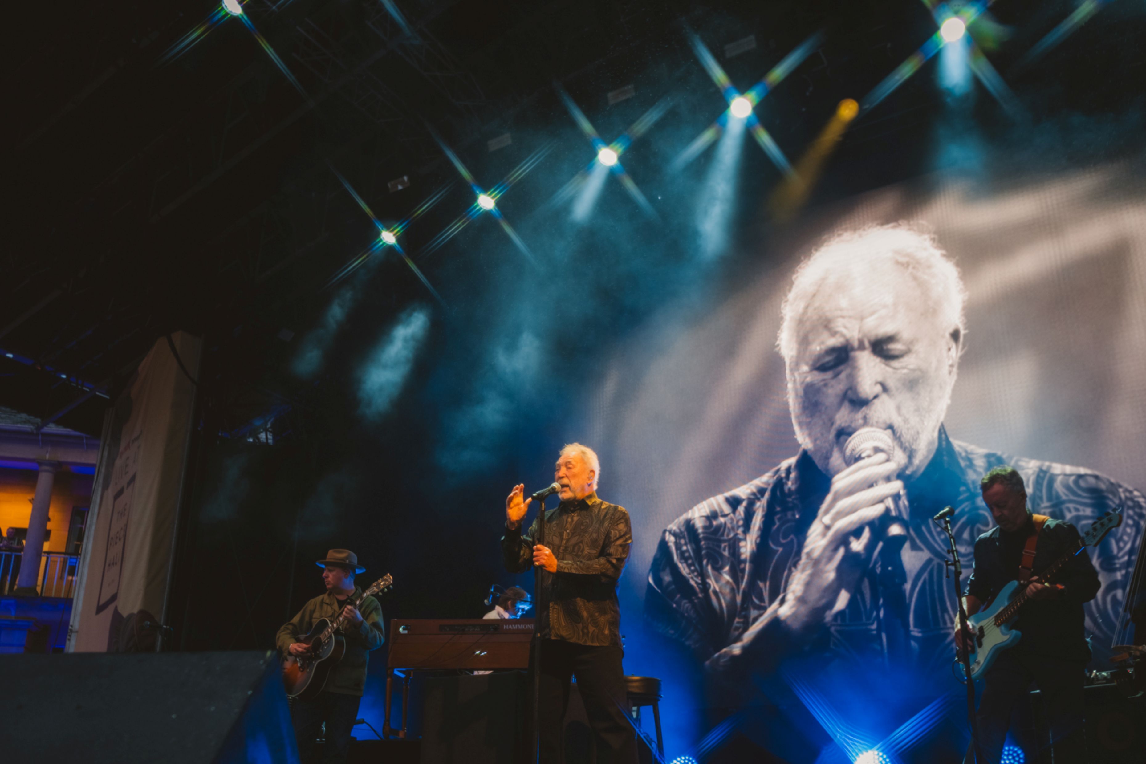 Singer performing on stage with large screen backdrop