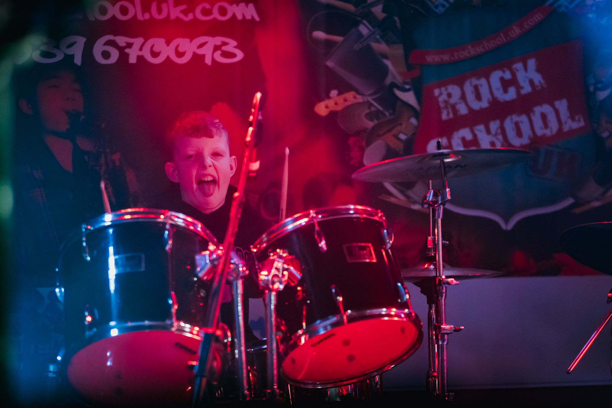 Young drummer enthusiastically playing in a rock music class