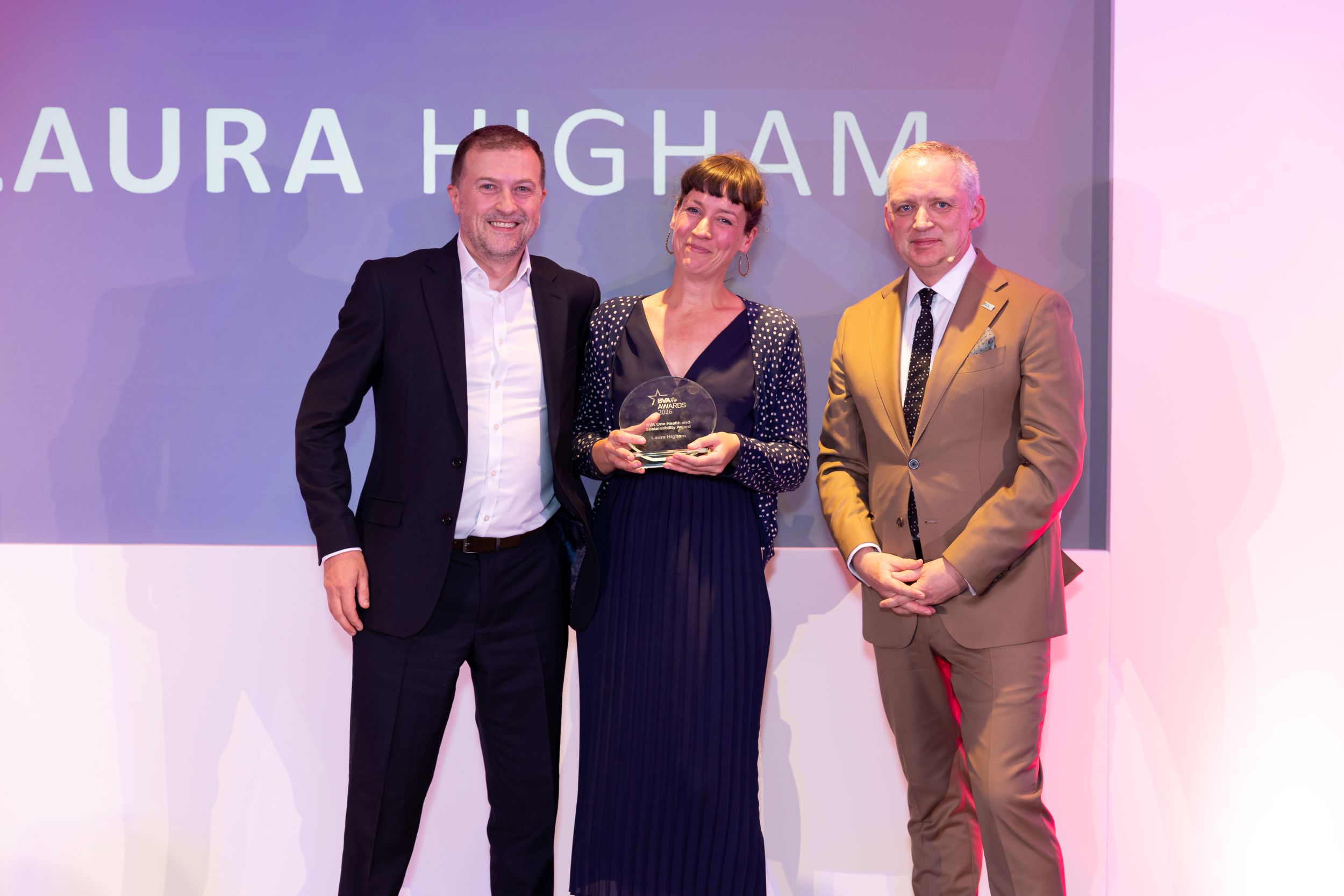 Three people in formal attire at an awards ceremony