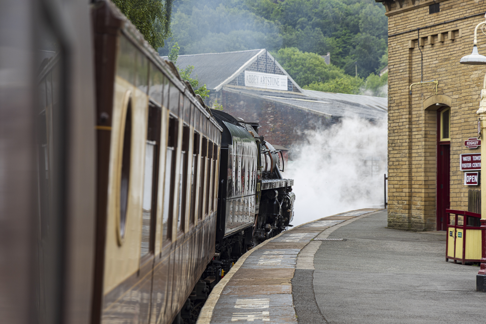 Steam train arriving at vintage Yorkshire station with smoke