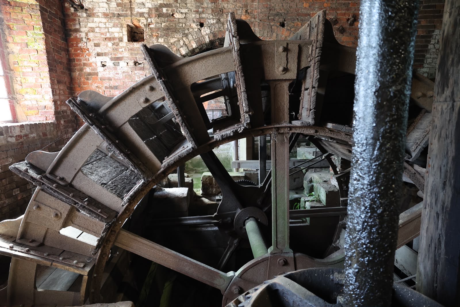 Historic waterwheel inside a brick mill with weathered wood