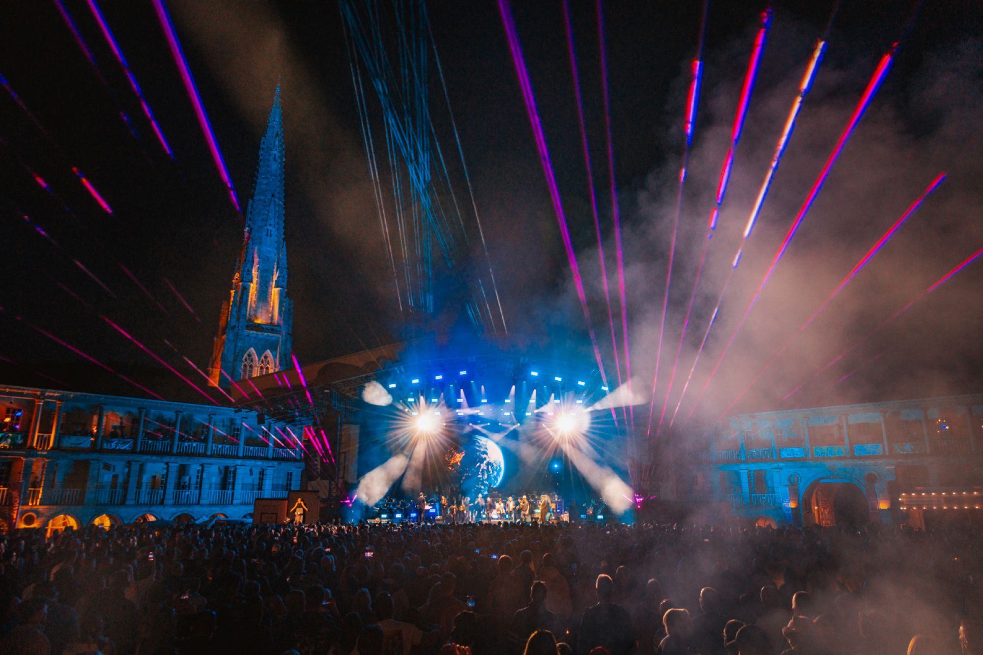 Nighttime music festival with colourful lights and church spire