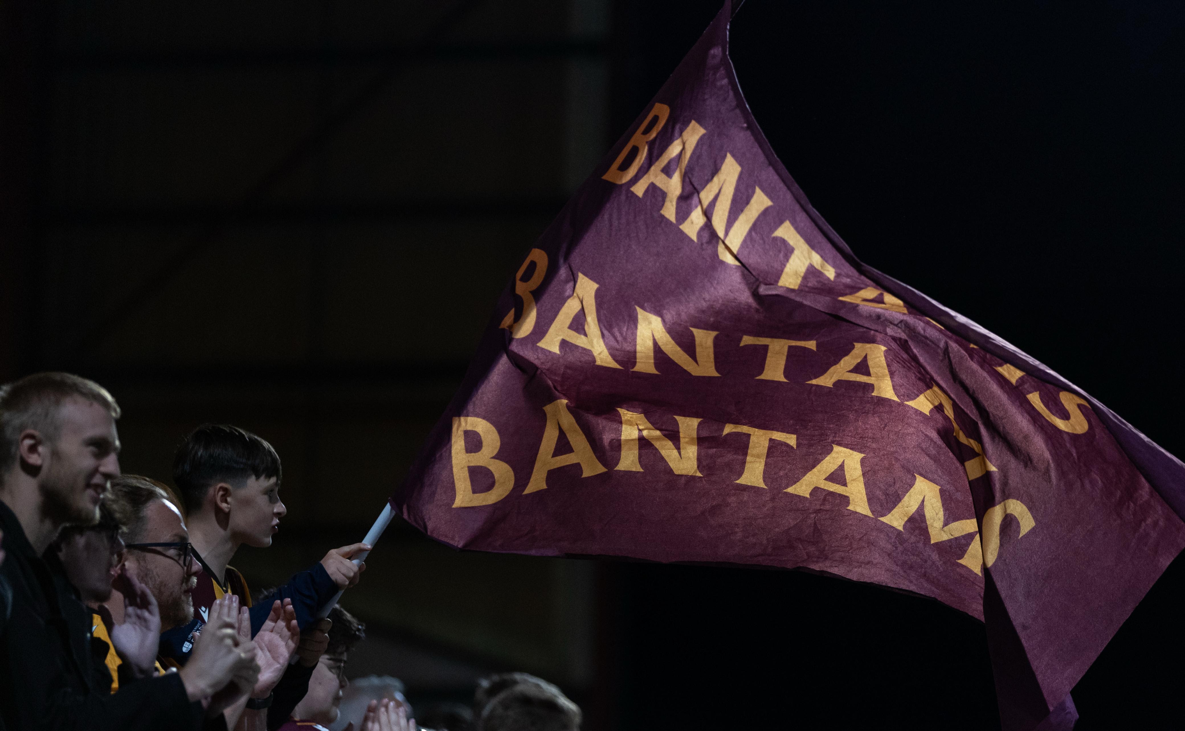 Fans waving maroon flag with 'Bantams' at night football match