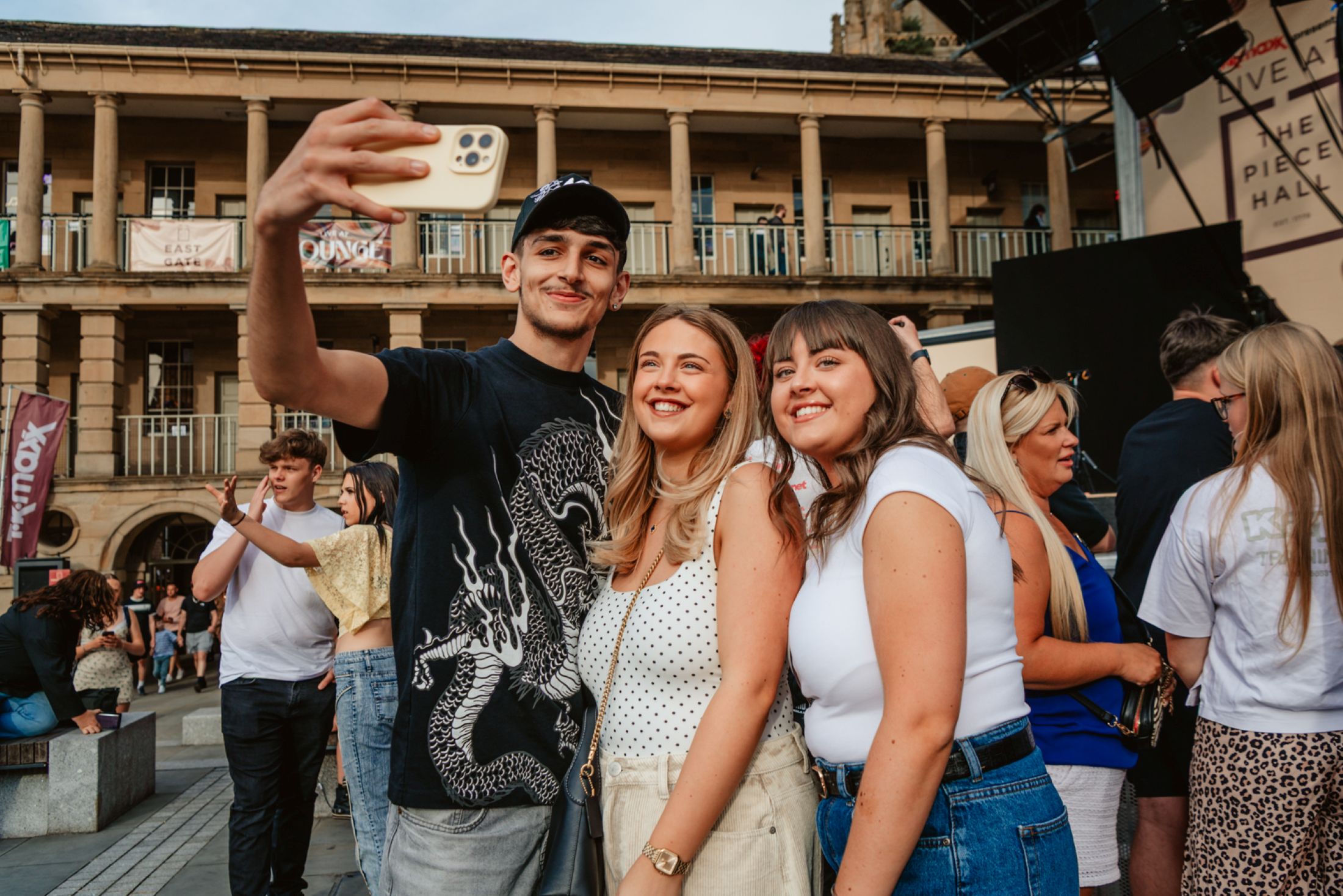 Three friends smiling and taking a selfie at an outdoor event