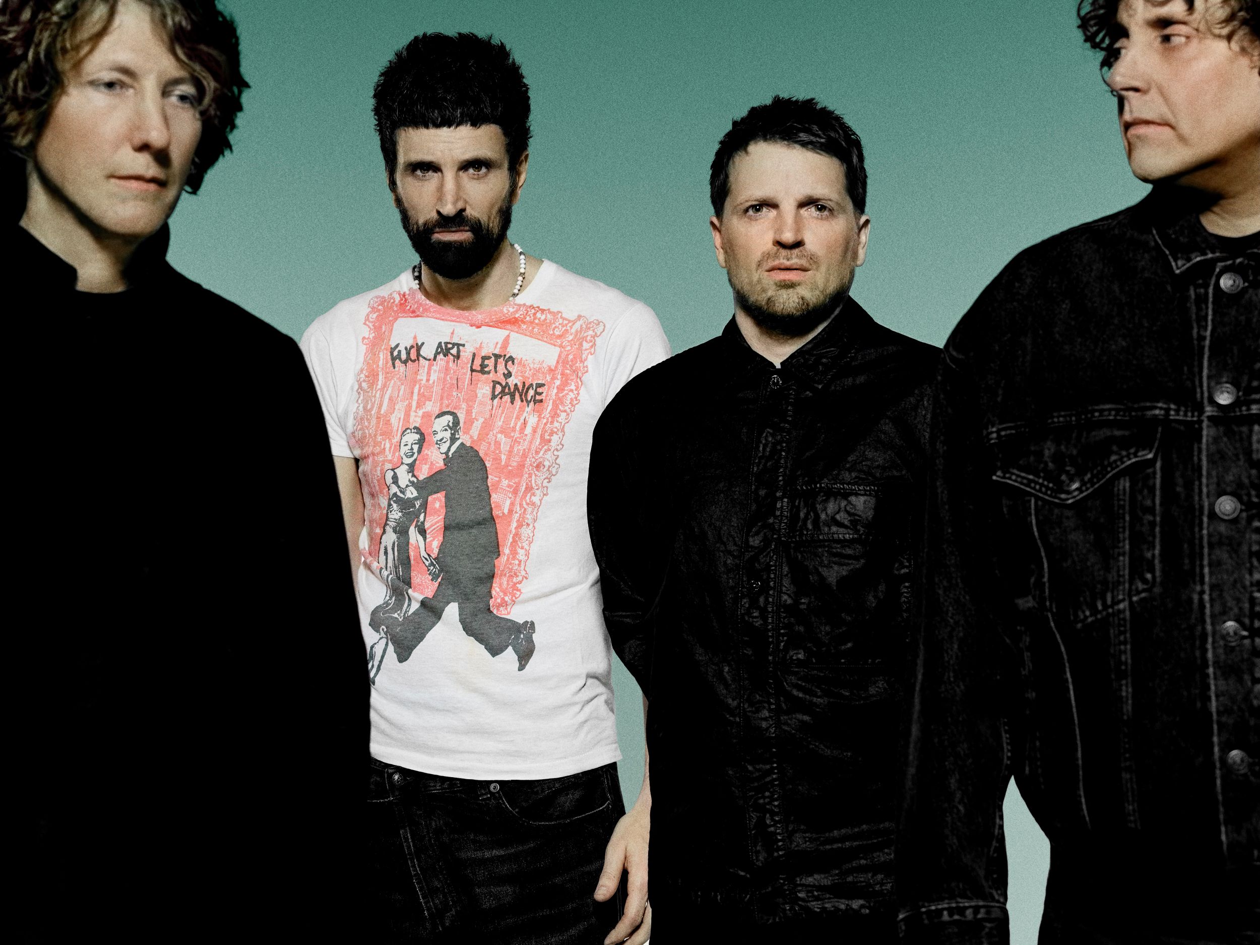 Four men in casual clothing against a green background