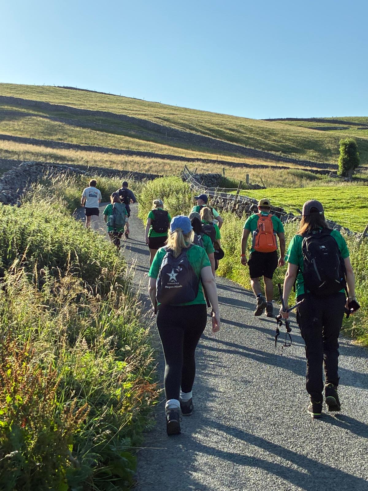 Group of hikers walking on a sunlit path in Yorkshire Dales