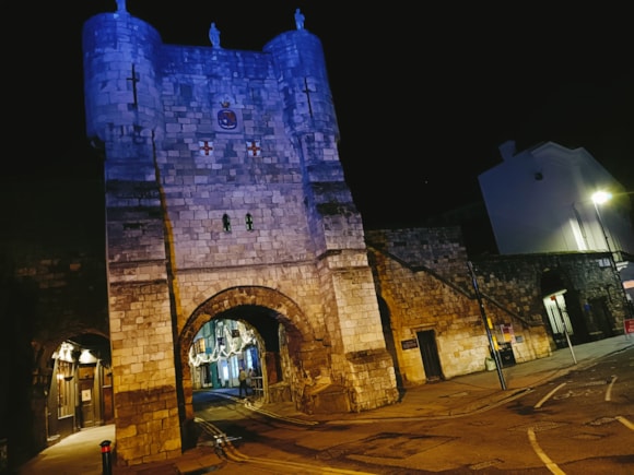 Illuminated medieval stone gatehouse with archway at night