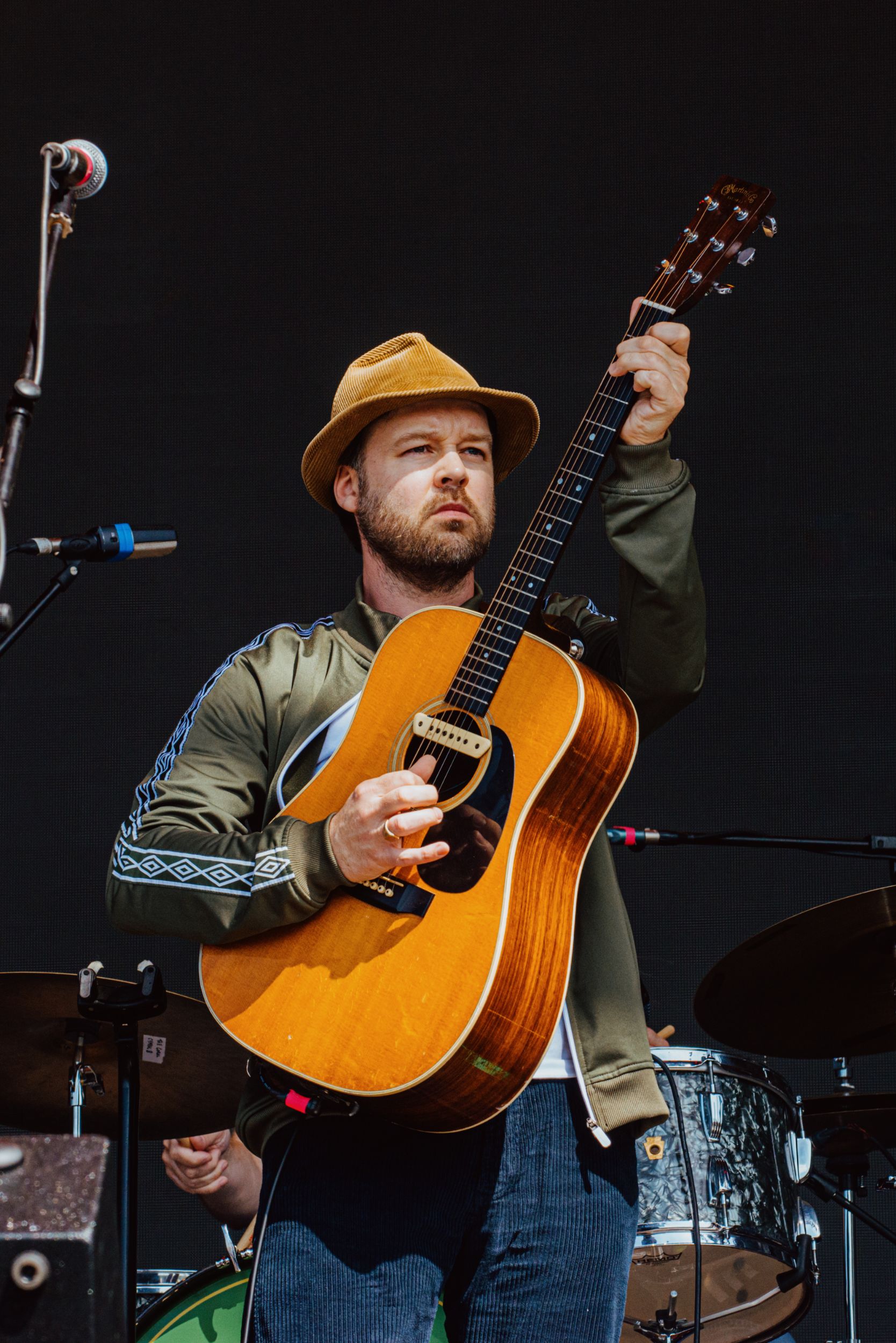 Musician wearing a hat playing an acoustic guitar on stage