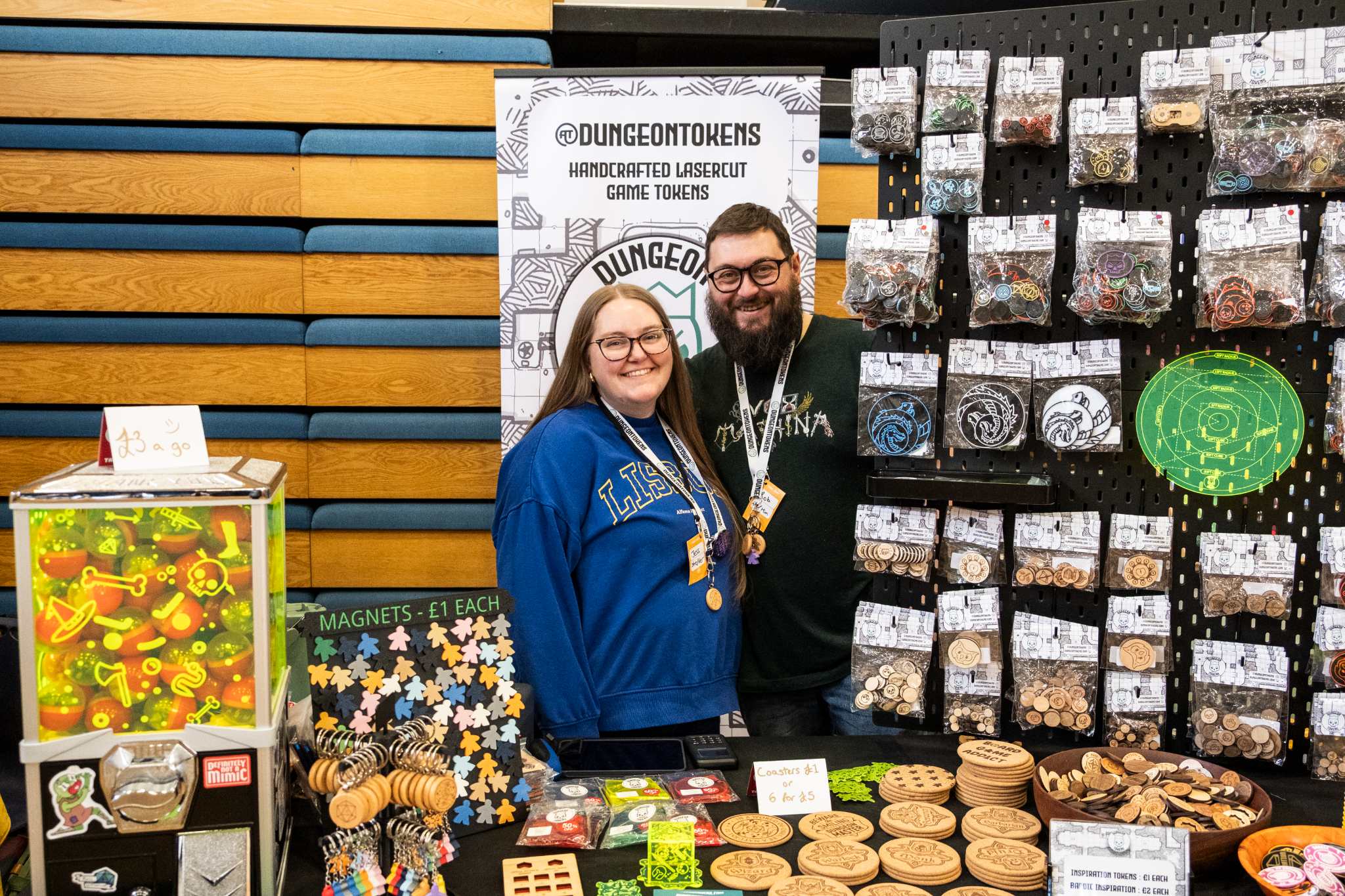 Two people smiling at a craft stall displaying handmade game tokens