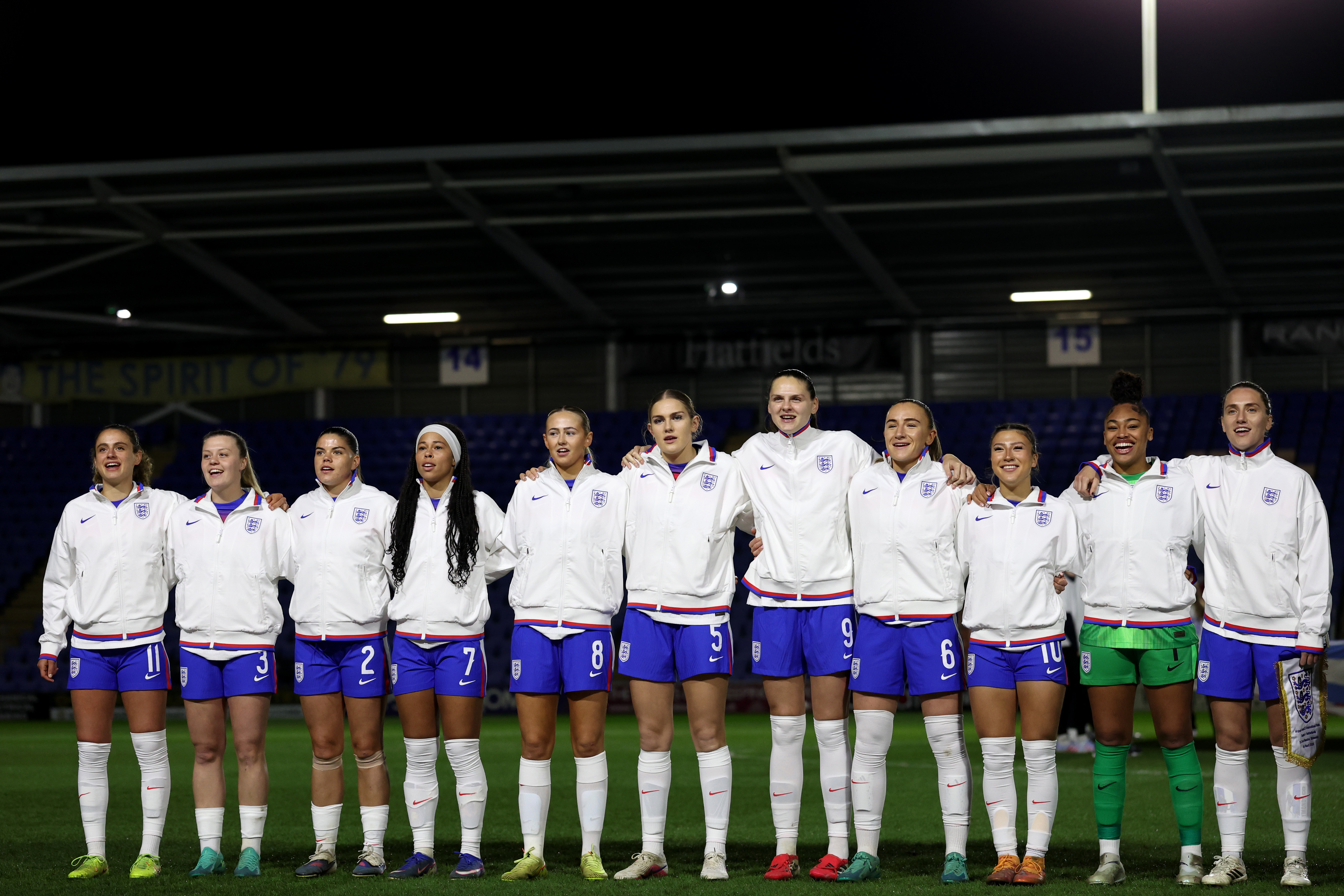Women's football team in white jerseys lined up on pitch