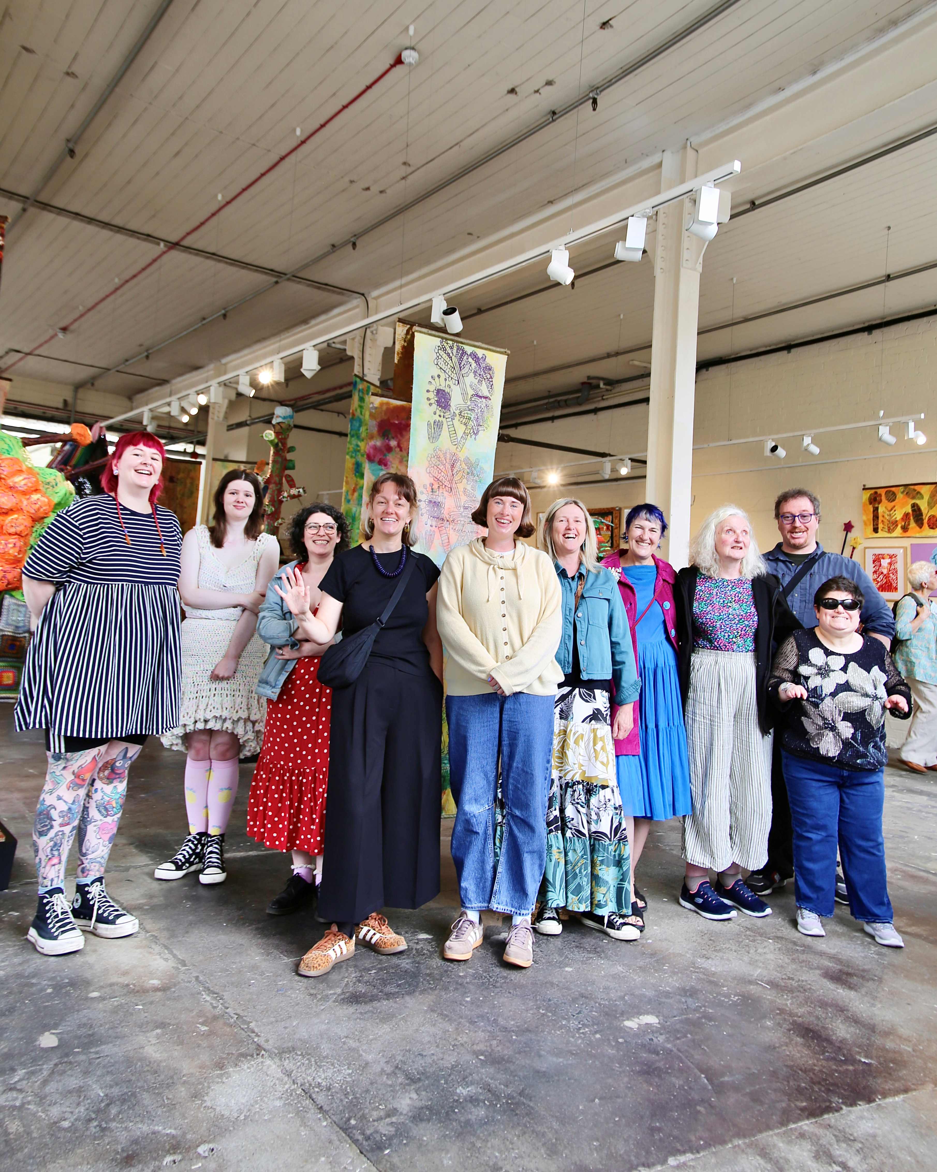 Group of smiling people in colorful attire inside an art gallery