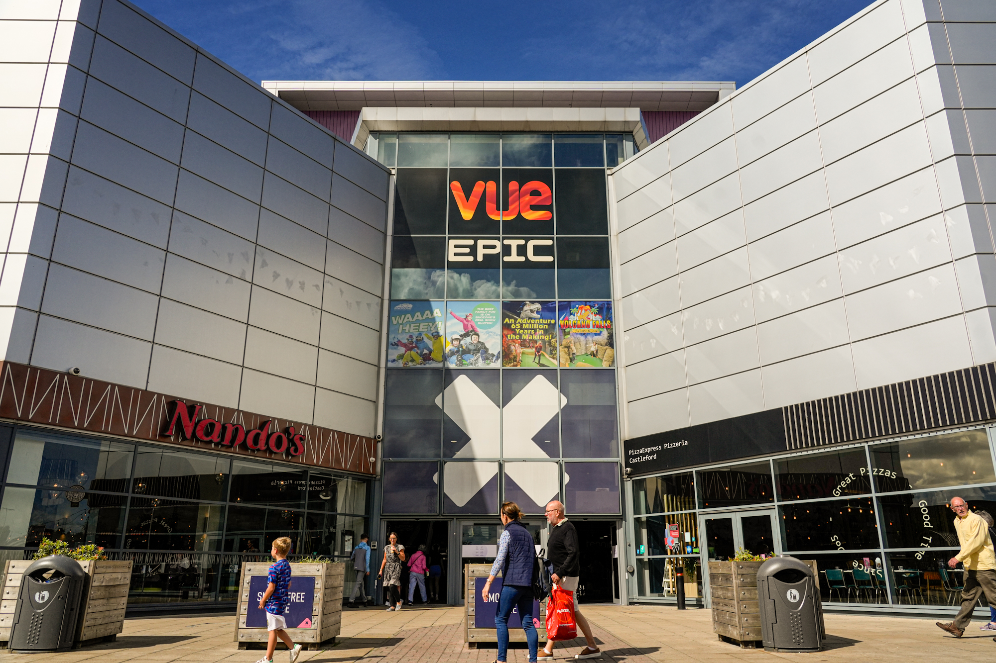 Modern shopping centre entrance with people walking by
