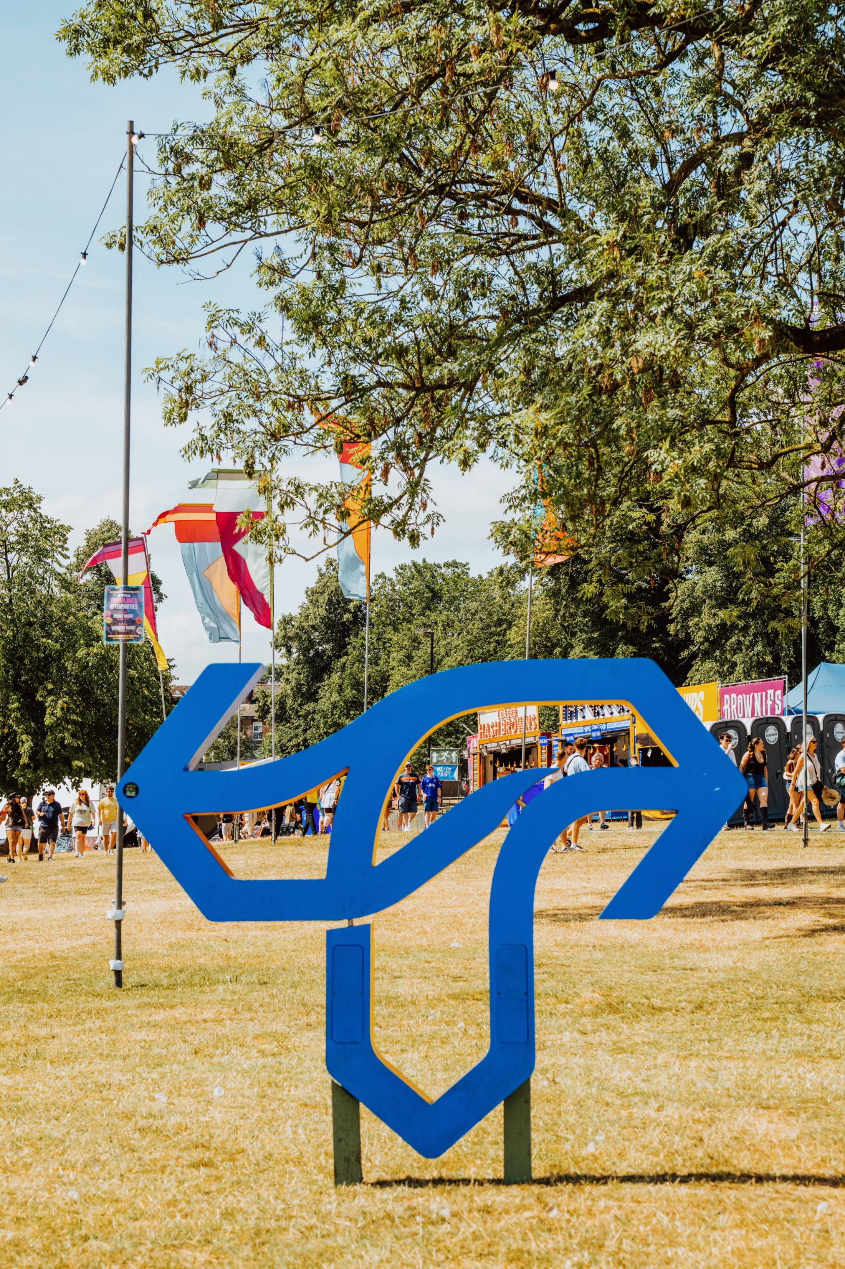 Colourful festival flags and unique blue sculpture on sunny day