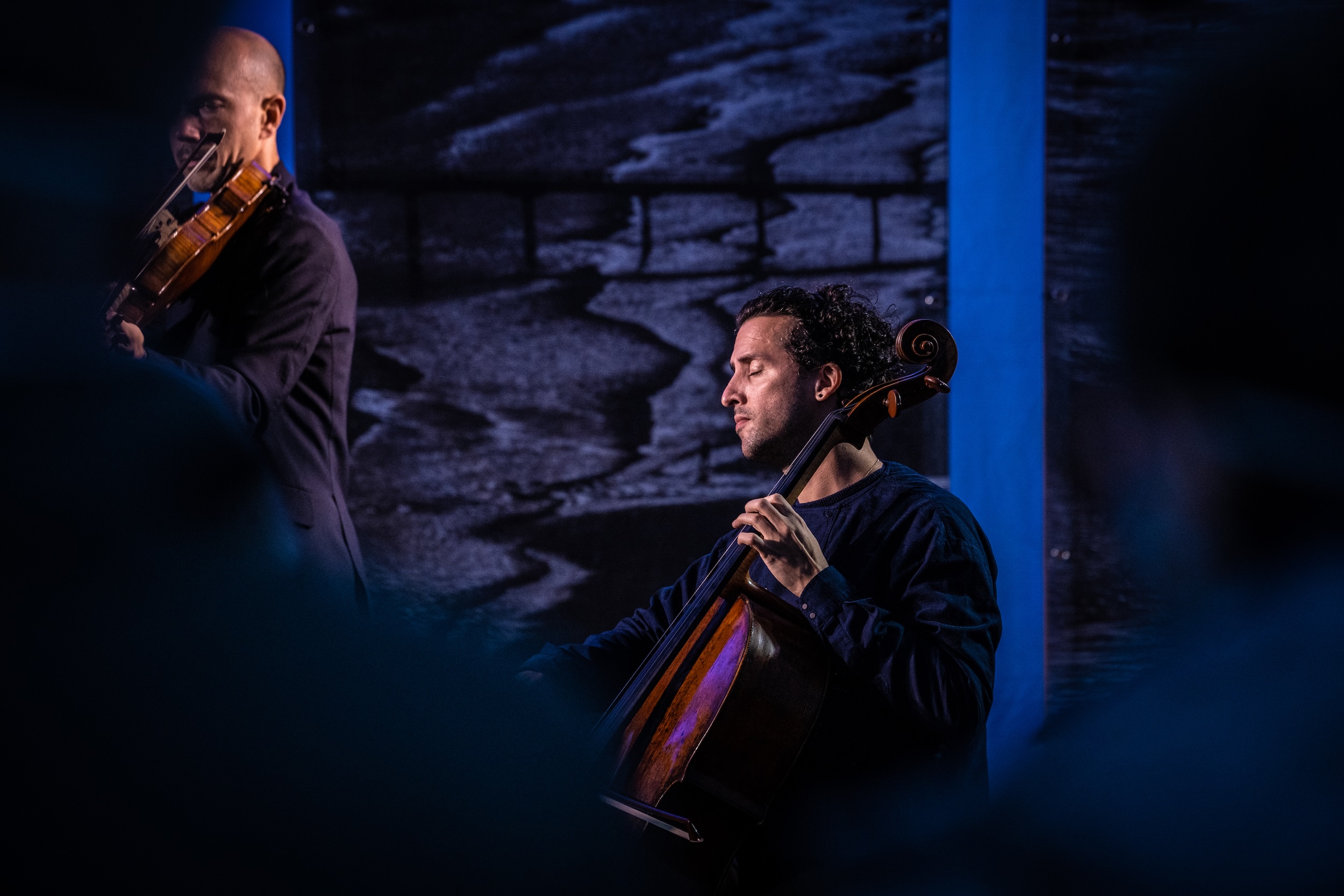 Cellist performing passionately on stage with dramatic lighting
