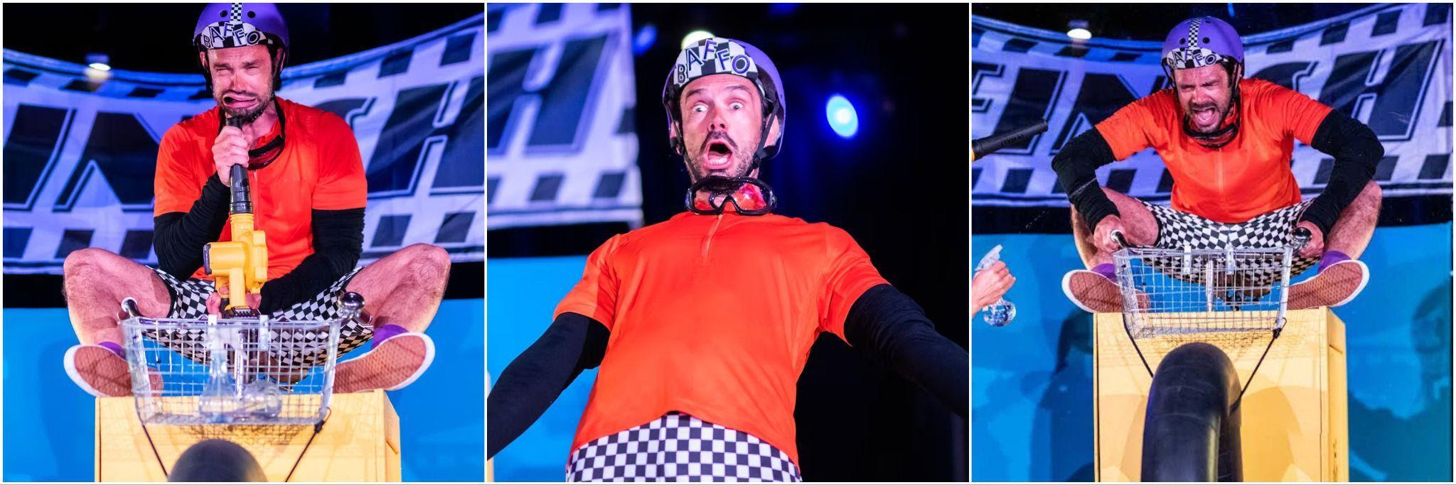 Man in orange shirt on stage wearing helmet with humorous expression