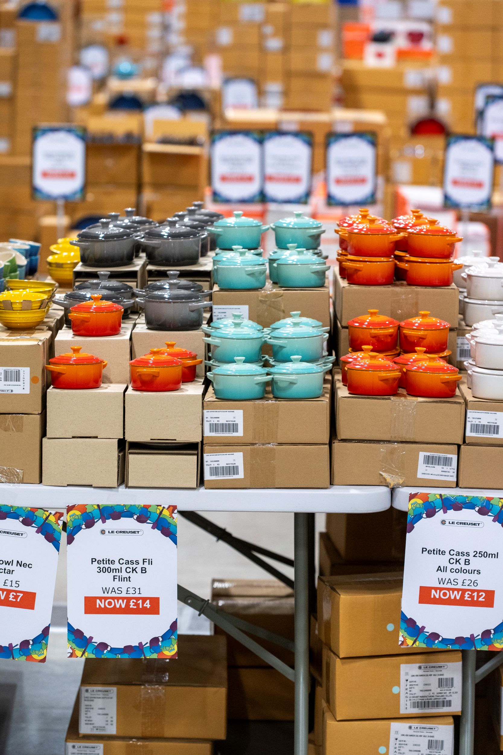 Stacks of colourful ceramic pots on display in a warehouse sale