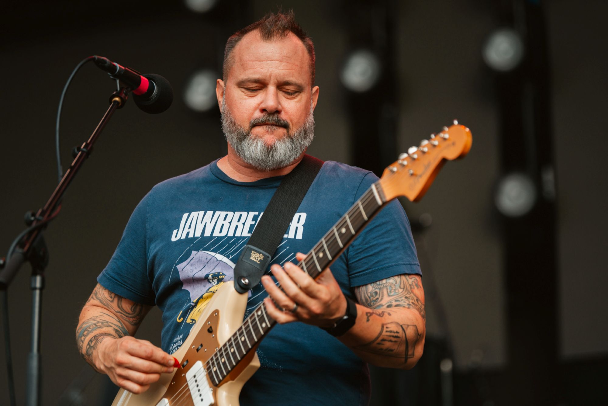 Musician with beard playing electric guitar on stage