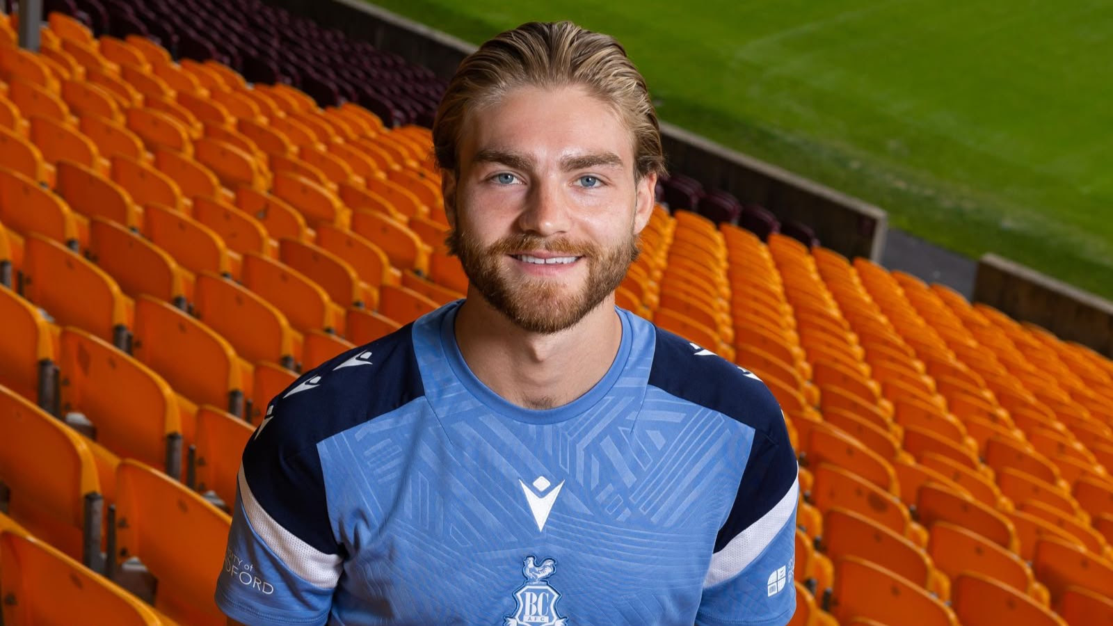 Smiling man in blue sports jersey in empty stadium seats