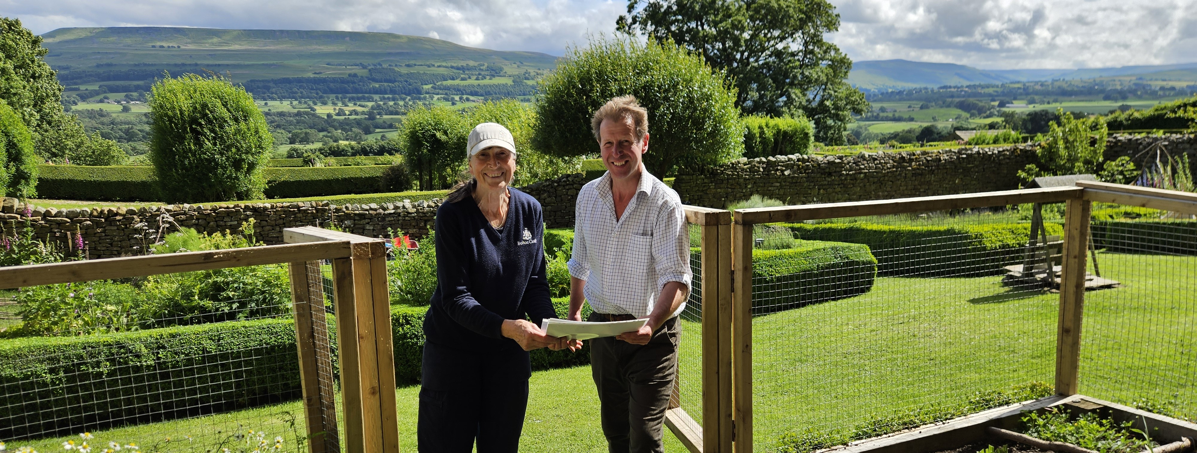 Couple standing in lush garden with rolling hills in background