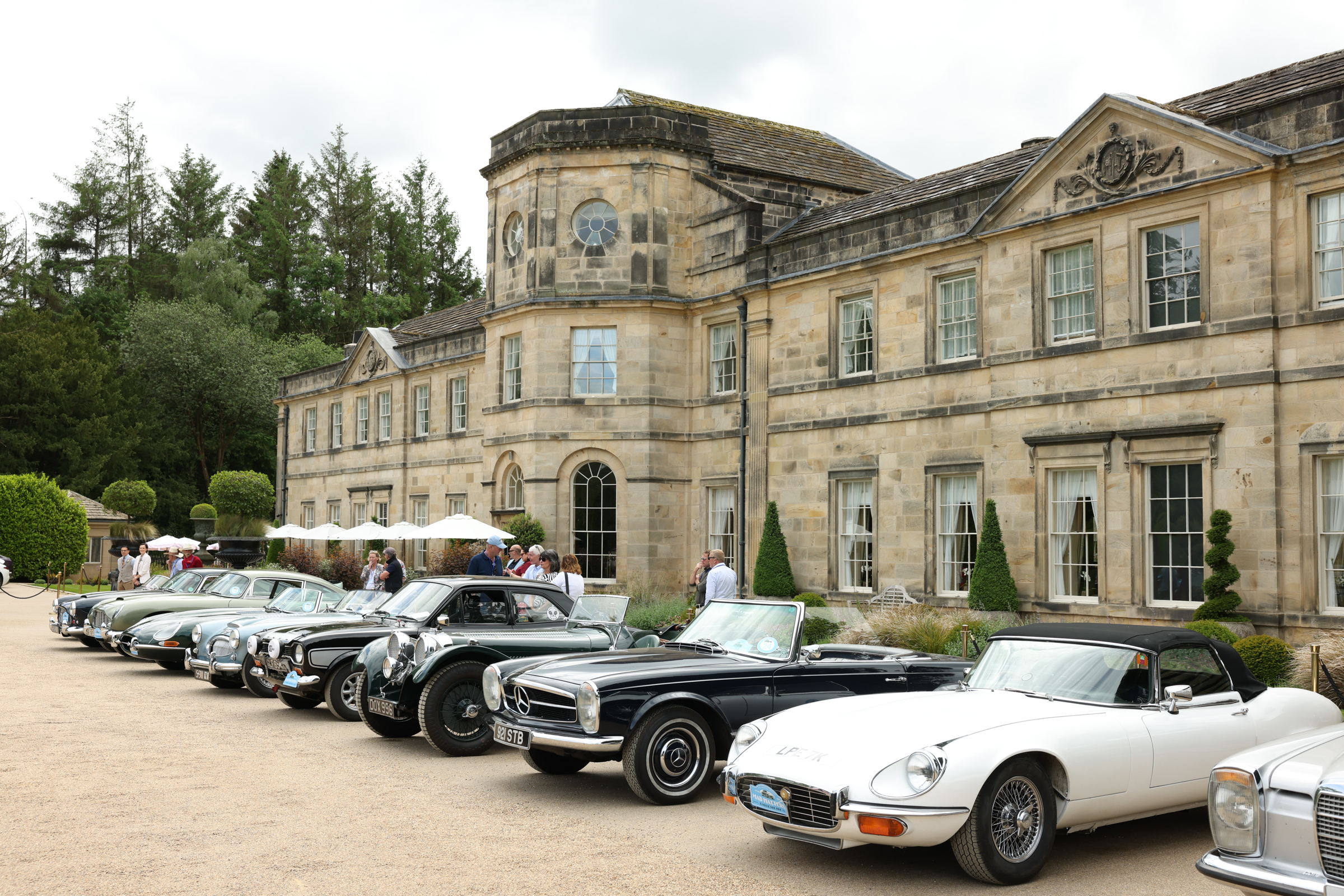 Historic stone manor with classic cars parked in front