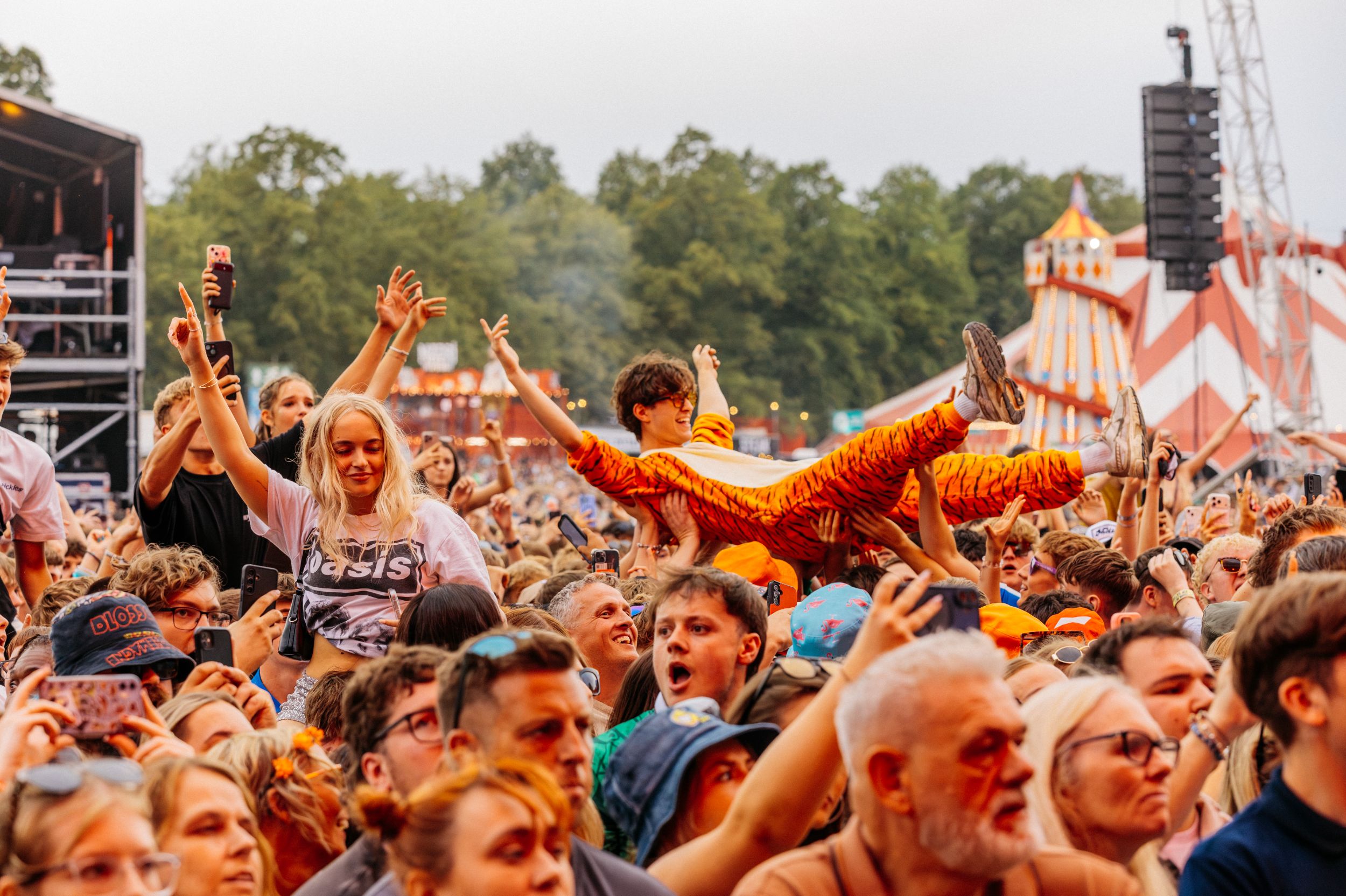 Festival crowd with vibrant outfits and amusement park in background