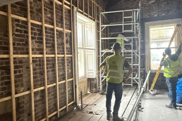 Workers in high-visibility vests renovating a historic brick room