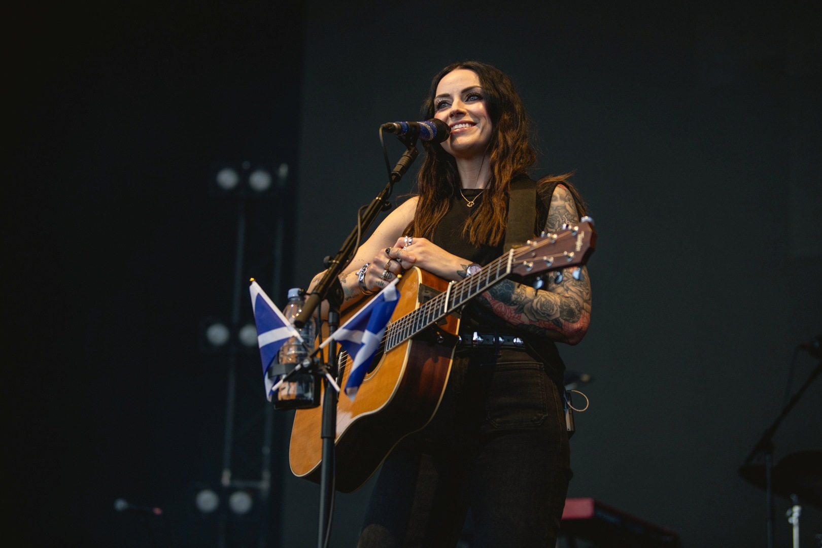 Musician playing guitar on stage with Scottish flags
