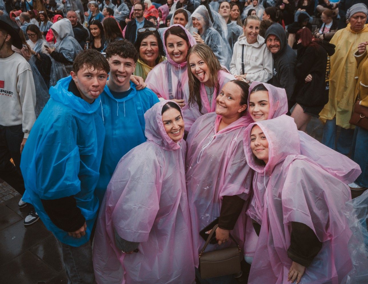 Group of smiling people in colorful rain ponchos at festival